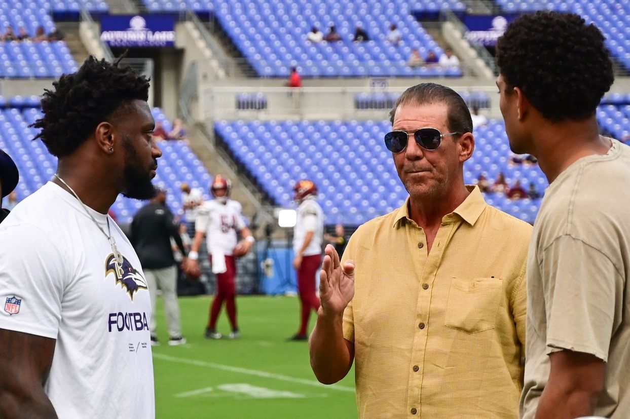 Baltimore Ravens owner Steve Bisciotti speaks with member of the team on the field before the game against the Washington Commanders at M&T Bank Stadium.