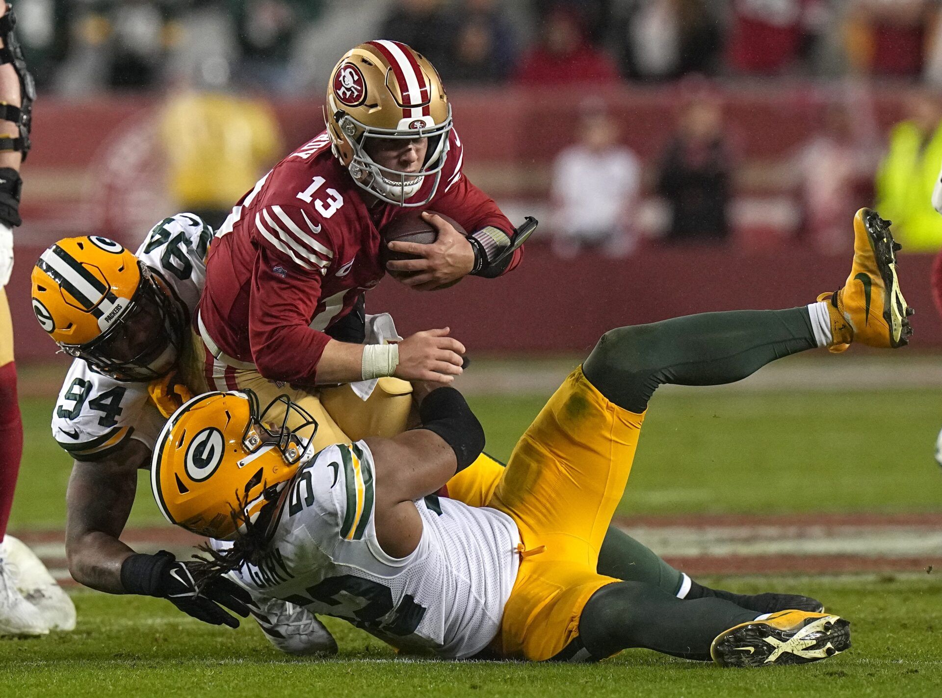 San Francisco 49ers quarterback Brock Purdy (13) is tackled by Green Bay Packers defensive end Karl Brooks (94) and Rashan Gary (52) after a one yard gain during the third quarter of their NFC divisional playoff game