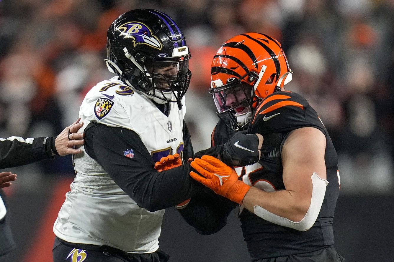 Baltimore Ravens offensive tackle Ronnie Stanley (79) grips the jersey of Cincinnati Bengals linebacker Logan Wilson (55) after a play in the fourth quarter during an NFL wild-card playoff football game between the Baltimore Ravens and the Cincinnati Bengals at Paycor Stadium.