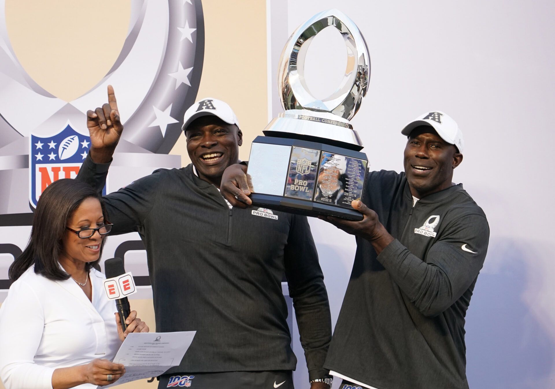 AFC legends coaches Bruce Smith (center) and Terrell Davis (right) hoist the trophy during interview by ESPN sideline reporter Lisa Salters after the 2020 NFL Pro Bowl against the NFC at Camping World Stadium.