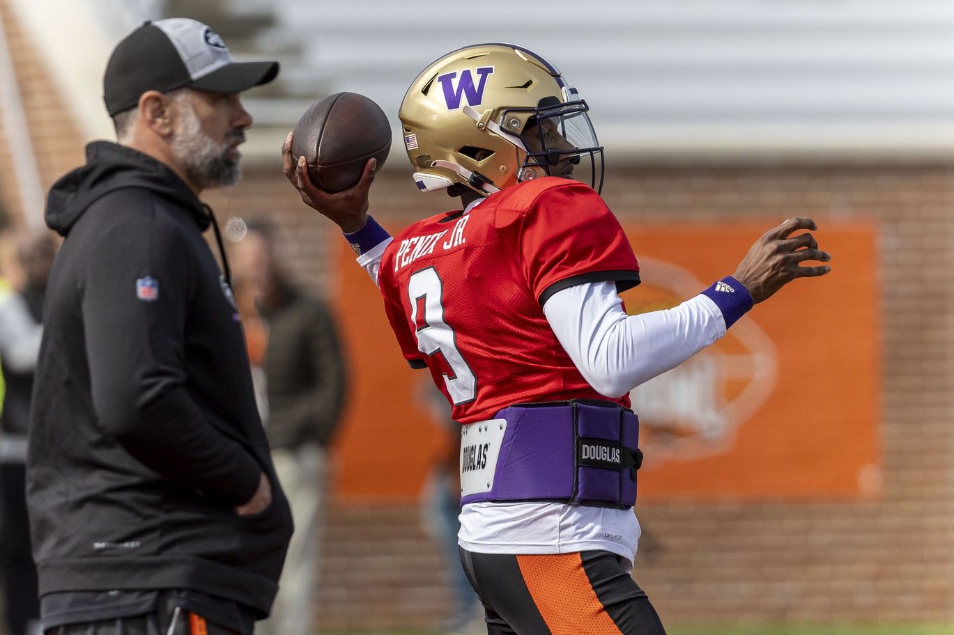 National quarterback Michael Penix Jr of Washington (9) throws with National head coach Jeff Ulbrich of the New York Jets watching during practice for the National team at Hancock Whitney Stadium.