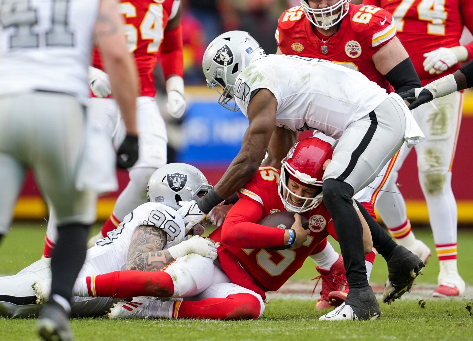 Kansas City Chiefs quarterback Patrick Mahomes (15) is tackled Las Vegas Raiders defensive end Maxx Crosby (98) and linebacker Divine Deablo (5) during the second half at GEHA Field at Arrowhead Stadium.