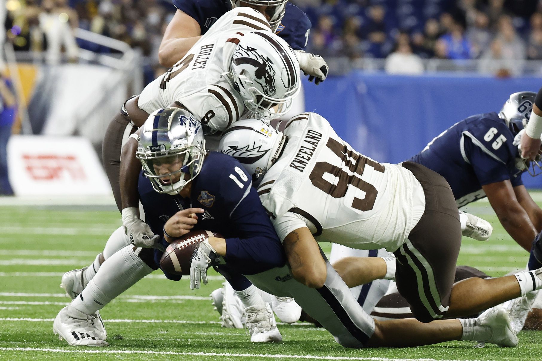 Nevada Wolf Pack quarterback Nate Cox (16) is sacked by Western Michigan Broncos defensive lineman Marshawn Kneeland (94) and defensive lineman Ralph Holley (8) in the first half during the 2021 Quick Lane Bowl at Ford Field.