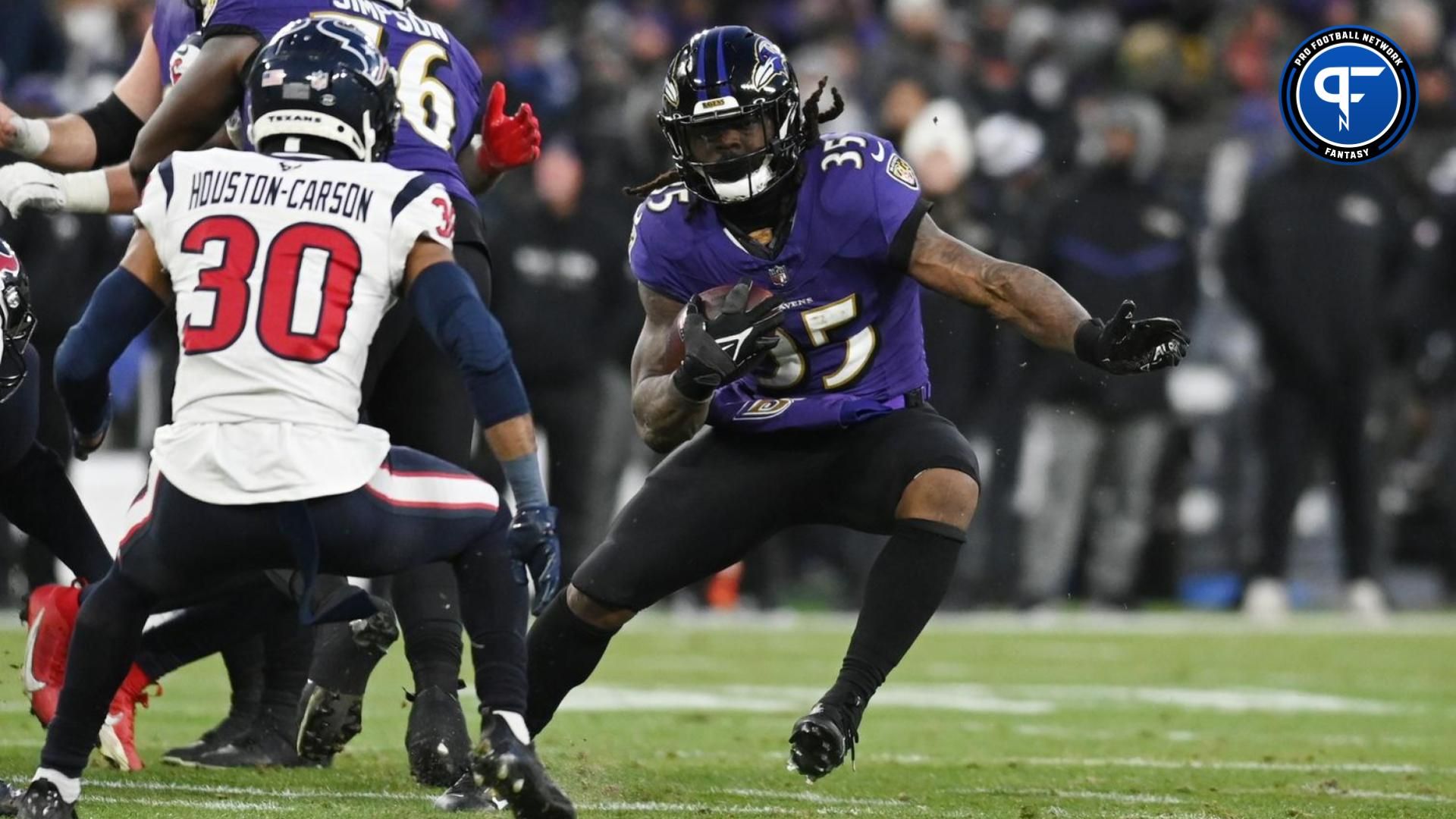 Baltimore Ravens running back Gus Edwards (35) runs the ball against Houston Texans safety DeAndre Houston-Carson (30) during the second quarter in a 2024 AFC divisional round game at M&T Bank Stadium.