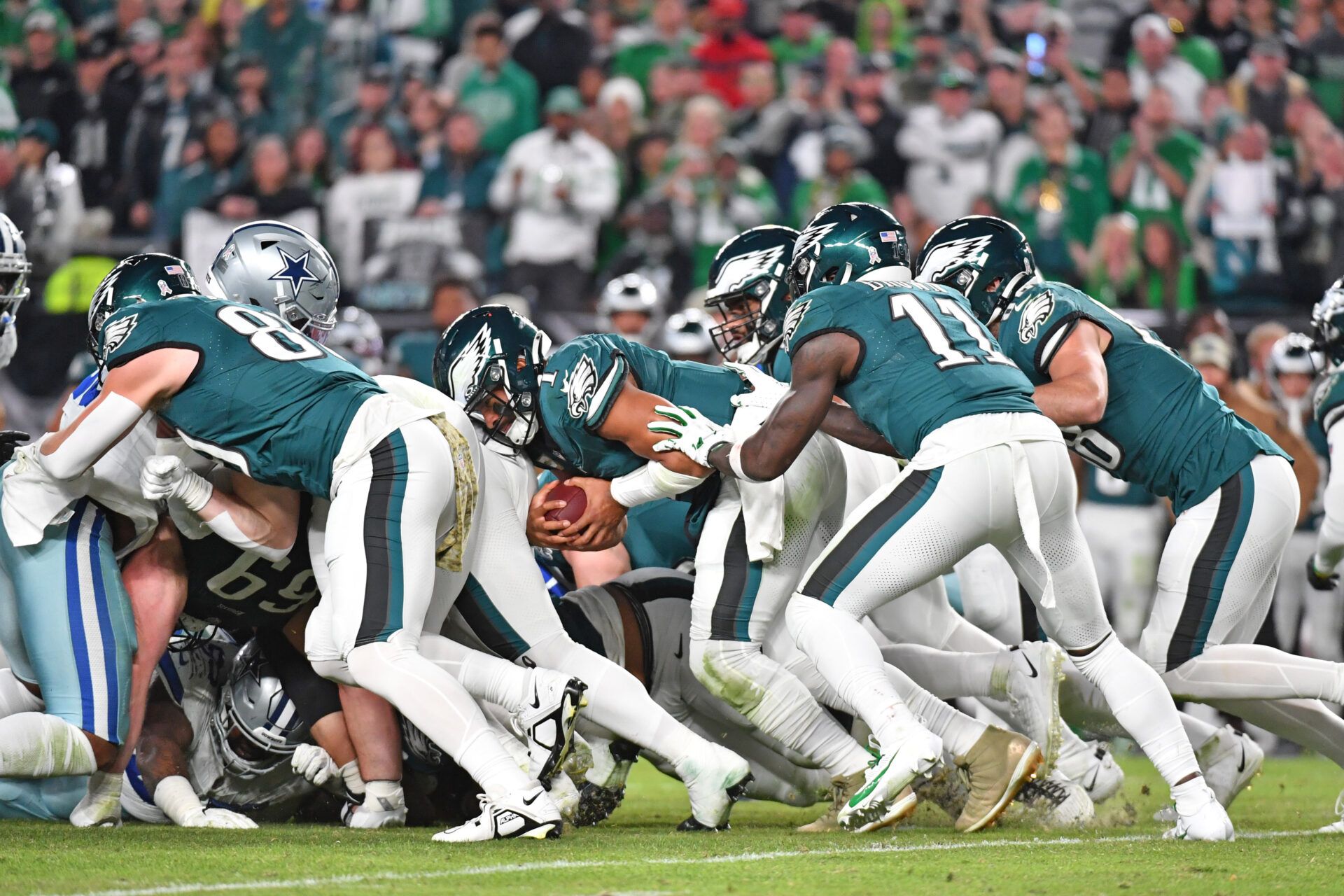 Philadelphia Eagles quarterback Jalen Hurts (1) picks up yardage a first down with a push from wide receiver A.J. Brown (11) and tight end Dallas Goedert (88) against the Dallas Cowboys at Lincoln Financial Field.