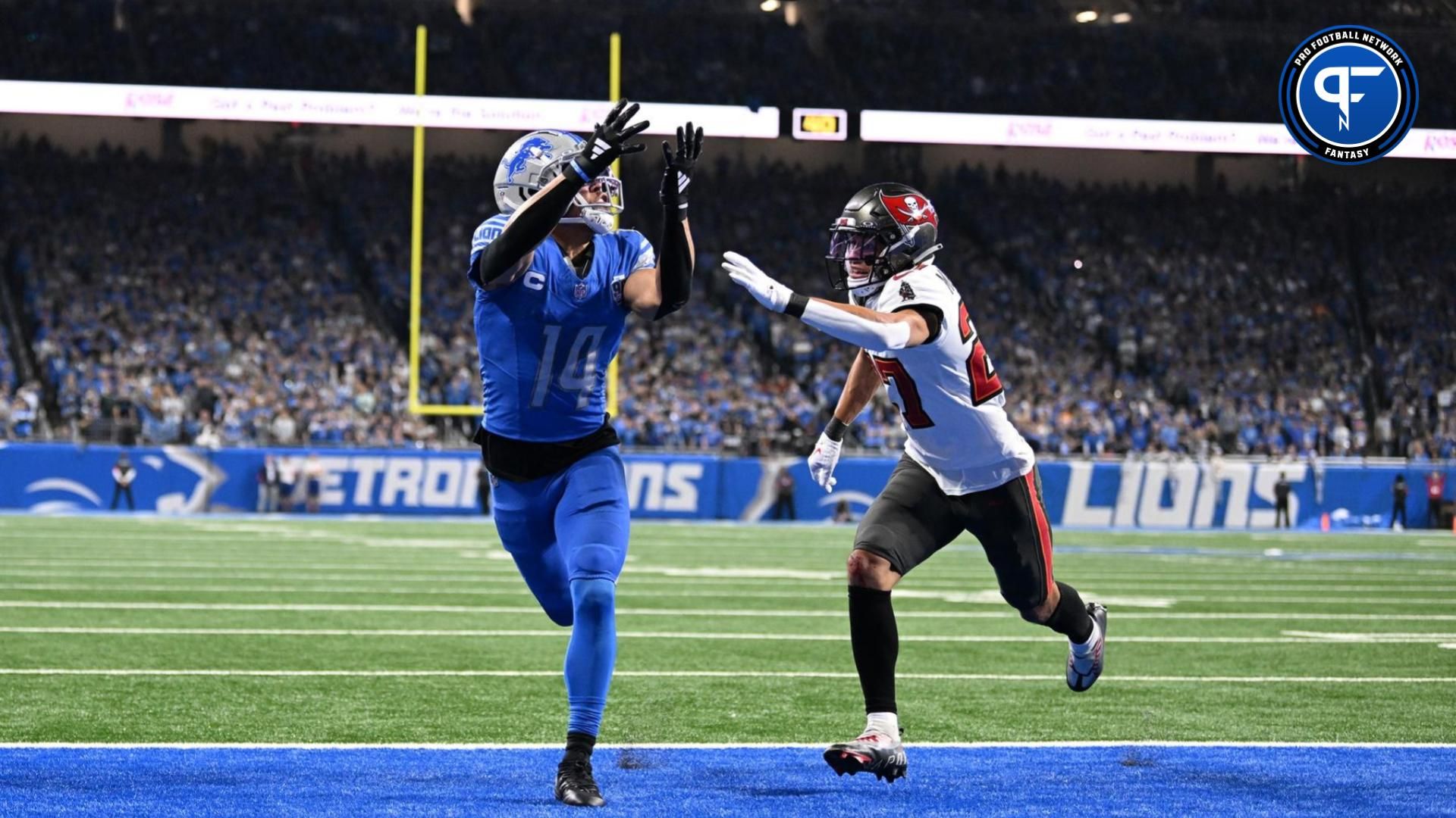 Detroit Lions wide receiver Amon-Ra St. Brown (14) makes a catch for a touchdown against Tampa Bay Buccaneers cornerback Zyon McCollum (27) during the second half in a 2024 NFC divisional round game at Ford Field.
