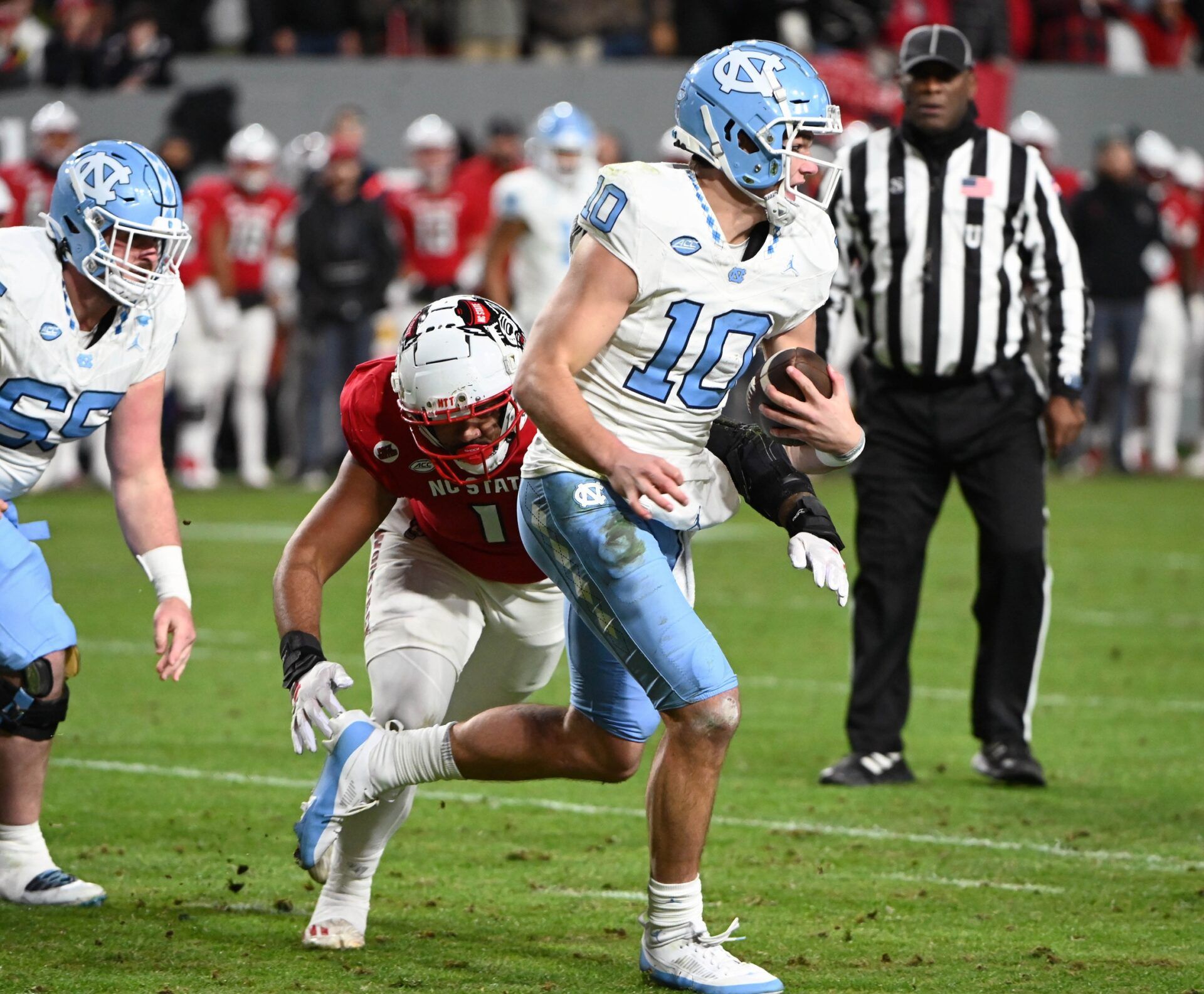 North Carolina Tar Heels quarterback Drake Maye (10) runs the ball against North Carolina State Wolfpack defensive end Davin Vann (1) during the first half at Carter-Finley Stadium.