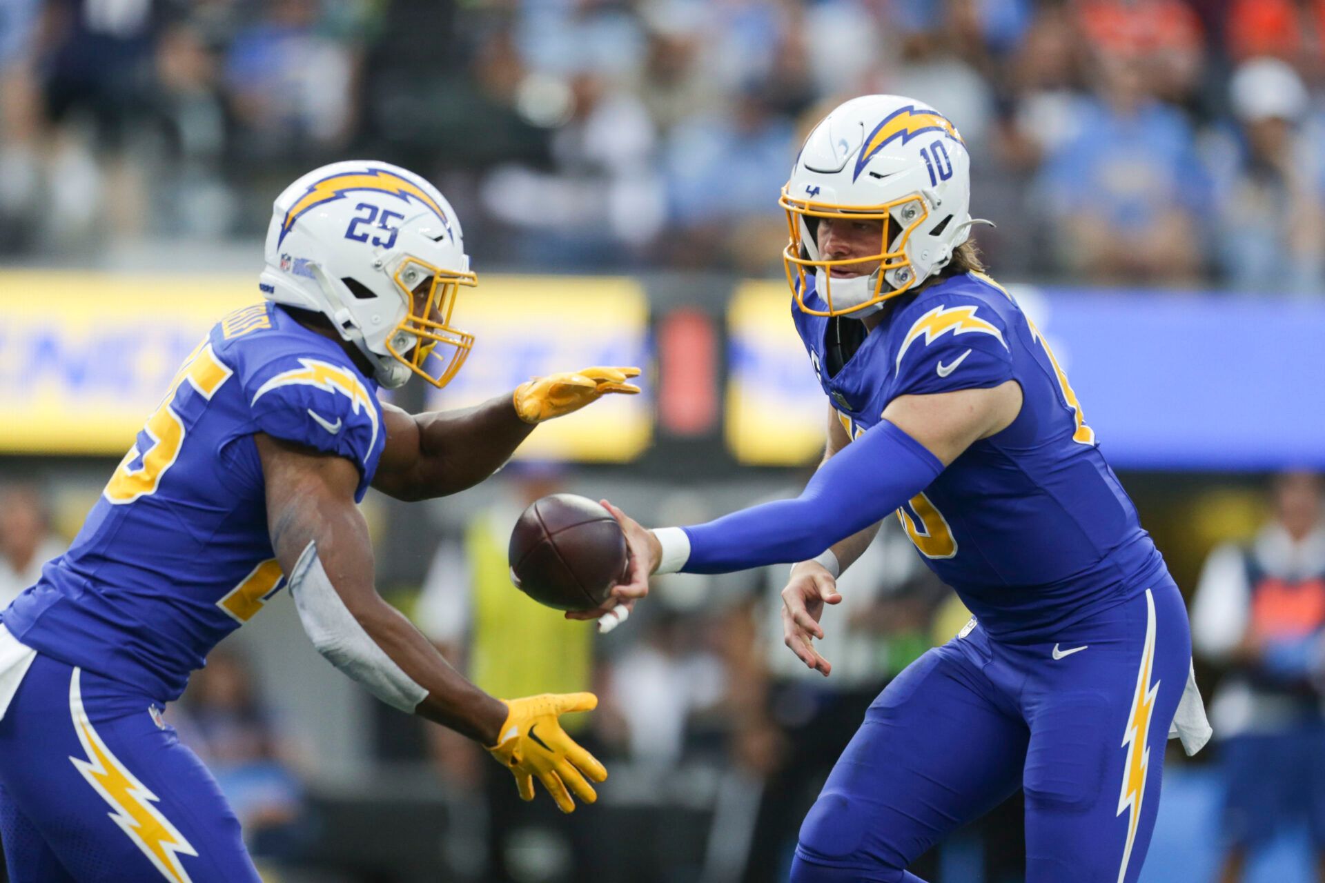 Los Angeles Chargers quarterback Justin Herbert (10) hands the ball to Los Angeles Chargers running back Joshua Kelley (25) during the first half in a game against the Denver Broncos at SoFi Stadium.