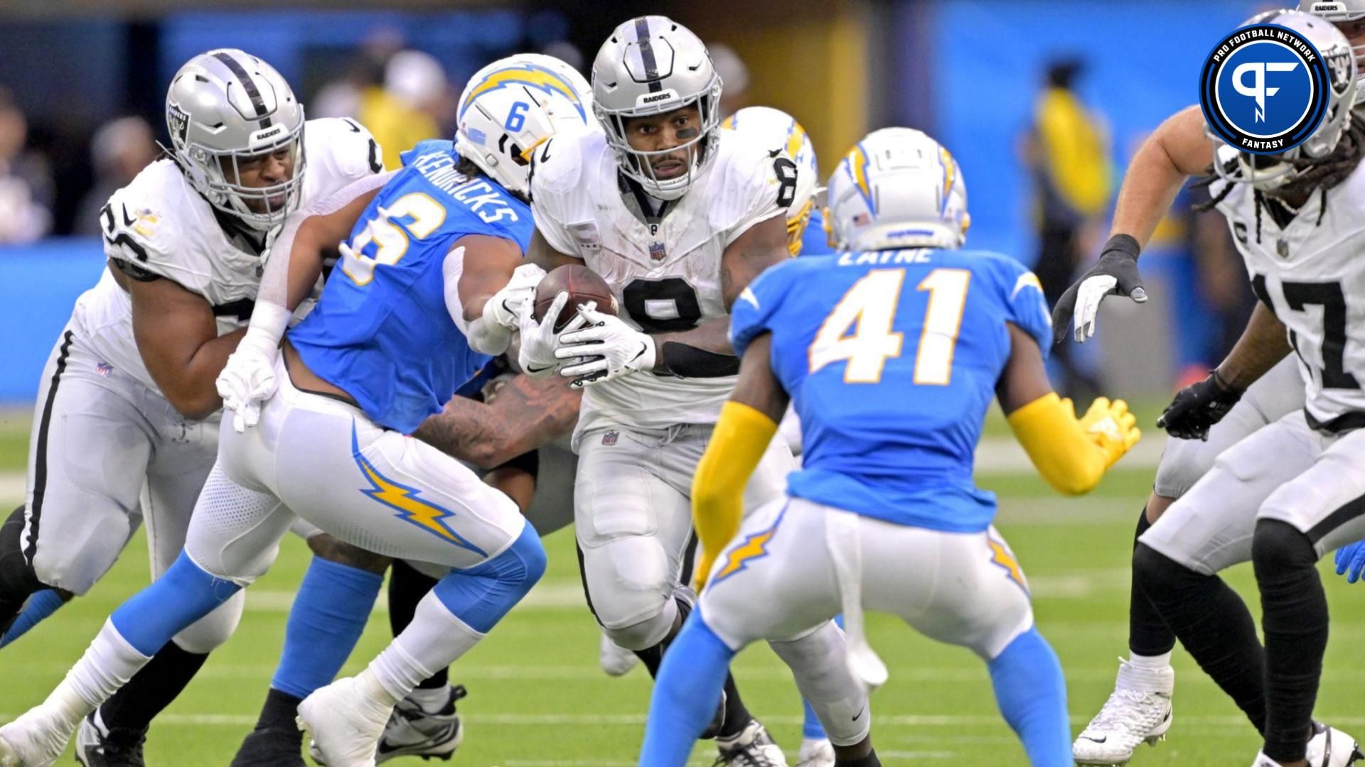 Las Vegas Raiders running back Josh Jacobs (8) carries the ball before he is stopped by Los Angeles Chargers linebacker Eric Kendricks (6) in the second half at SoFi Stadium.