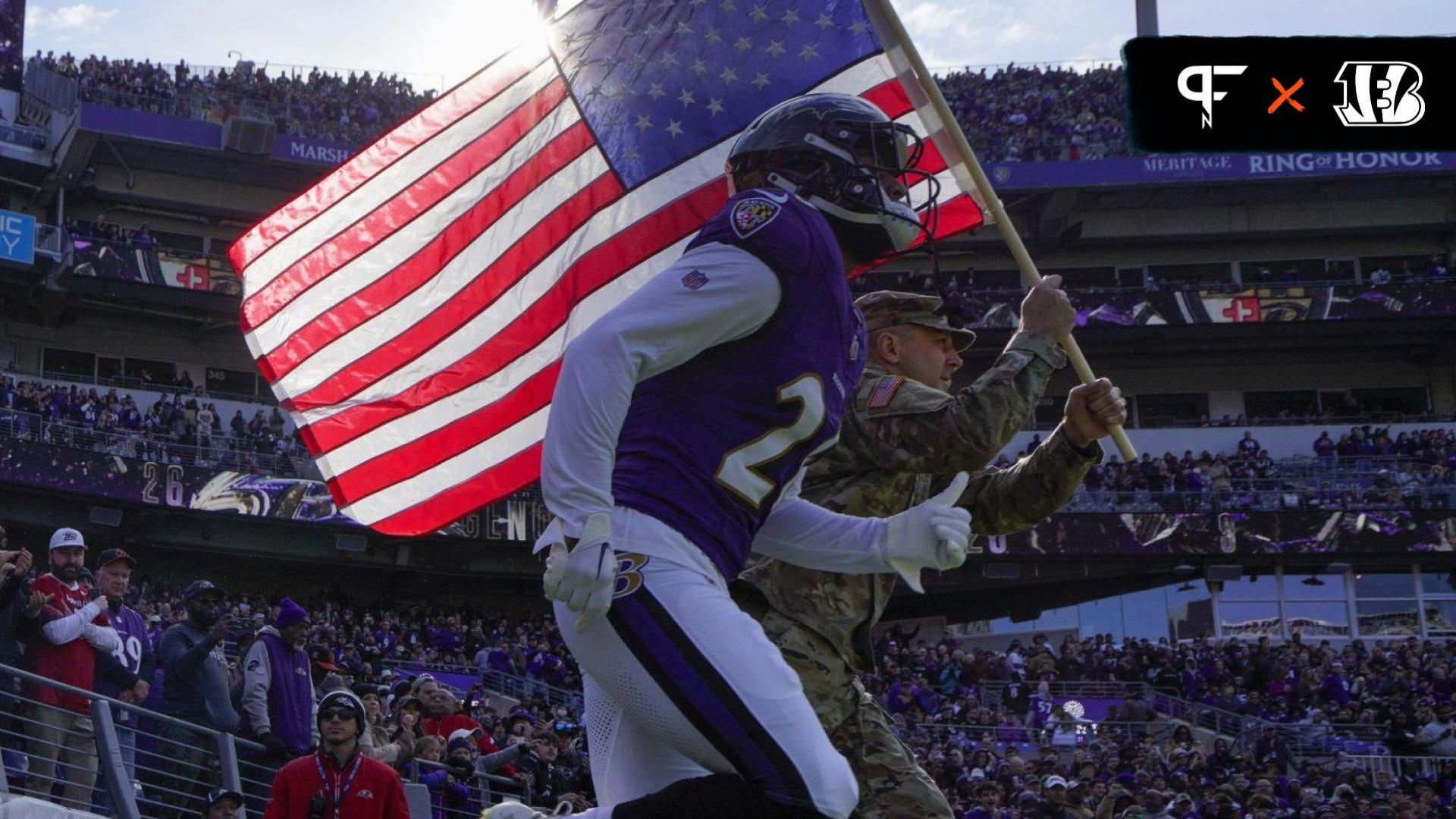 Baltimore Ravens safety Geno Stone (26) takes the field with a military service member before a game against the Cleveland Browns at M&T Bank Stadium.