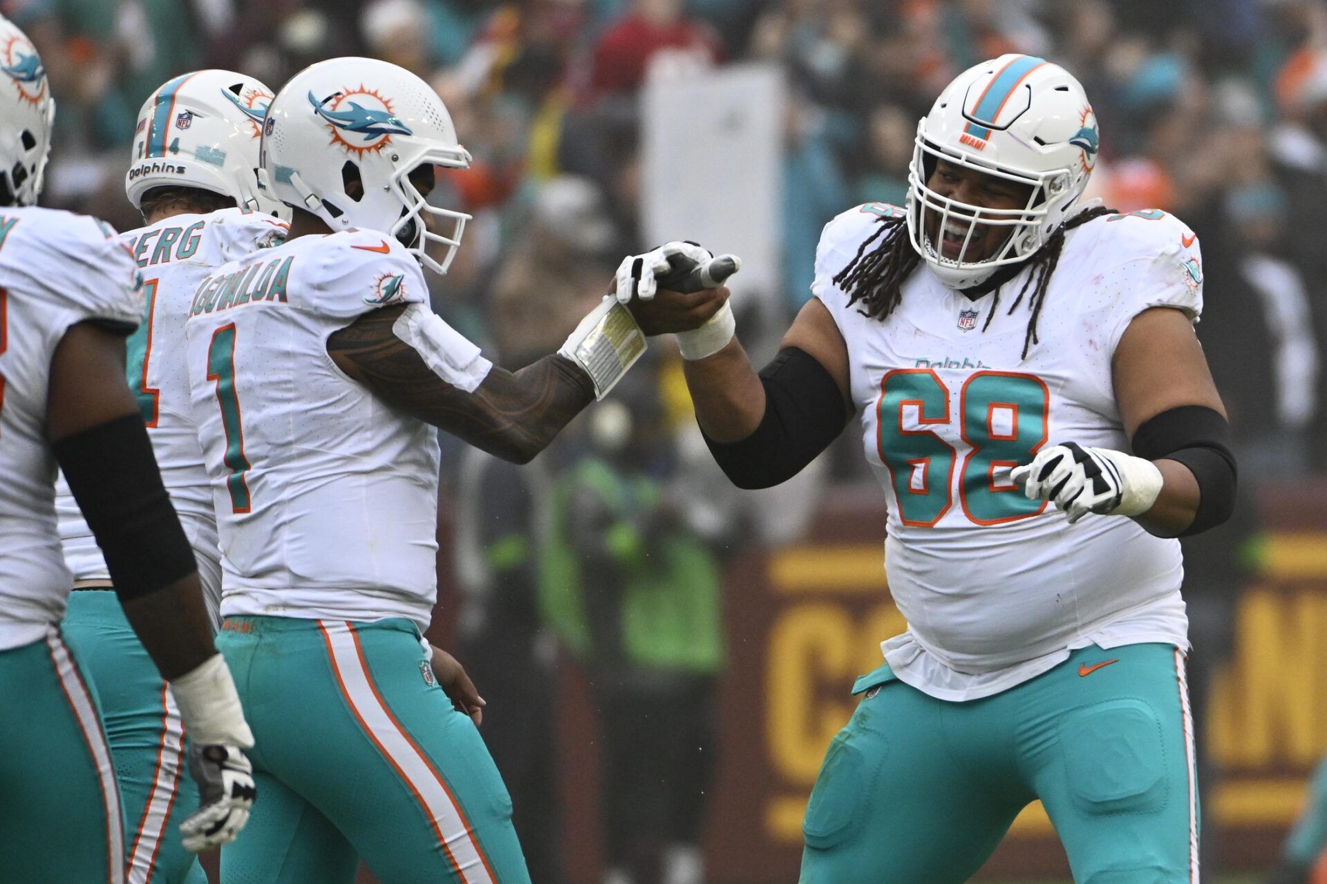 Miami Dolphins quarterback Tua Tagovailoa (1) celebrates with offensive tackle Robert Hunt (68) after a touchdown pass against the Washington Commanders during the first half at FedExField.