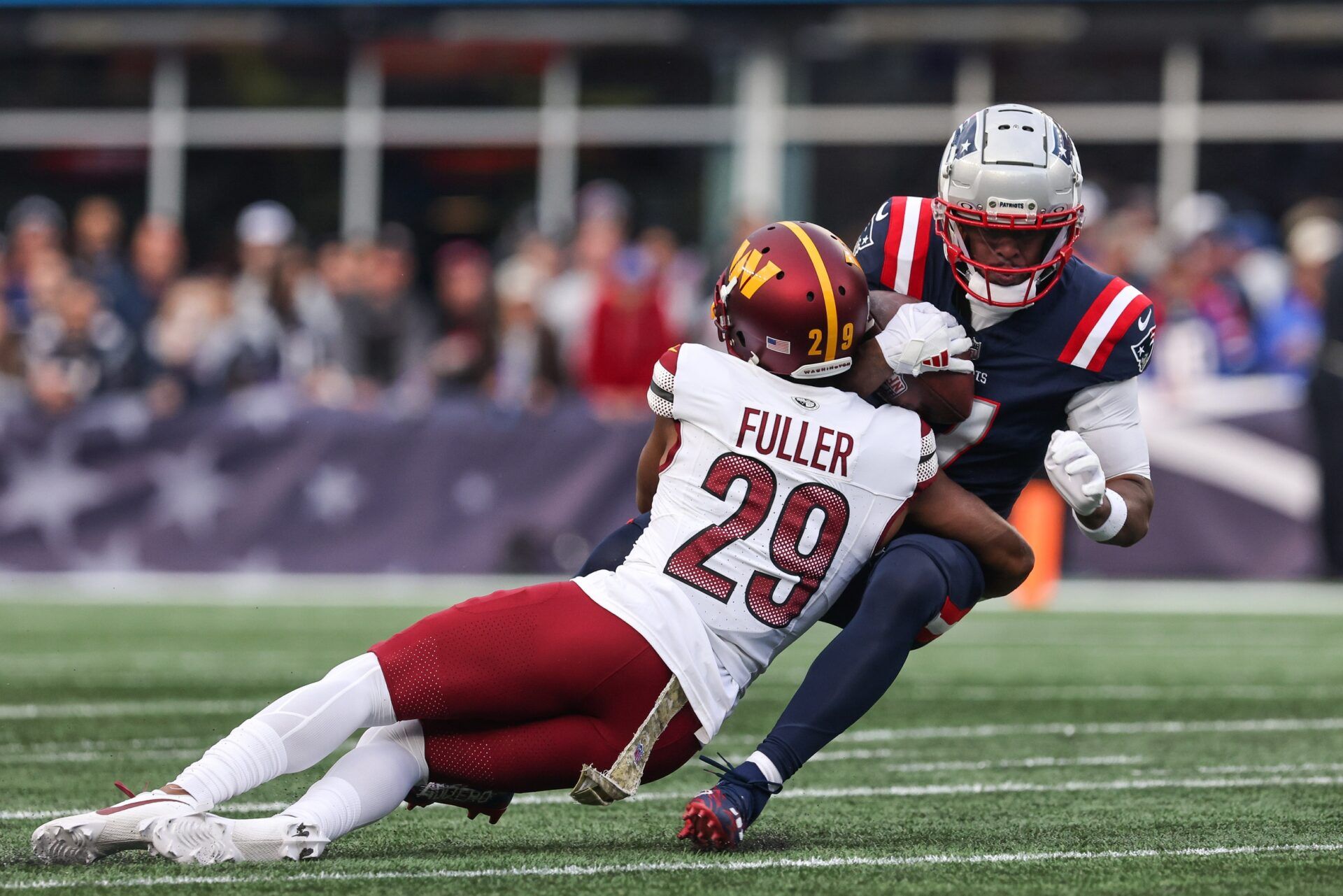 Washington Commanders cornerback Kendall Fuller (29) tackles New England Patriots receiver JuJu Smith-Schuster (7) during the second half at Gillette Stadium.