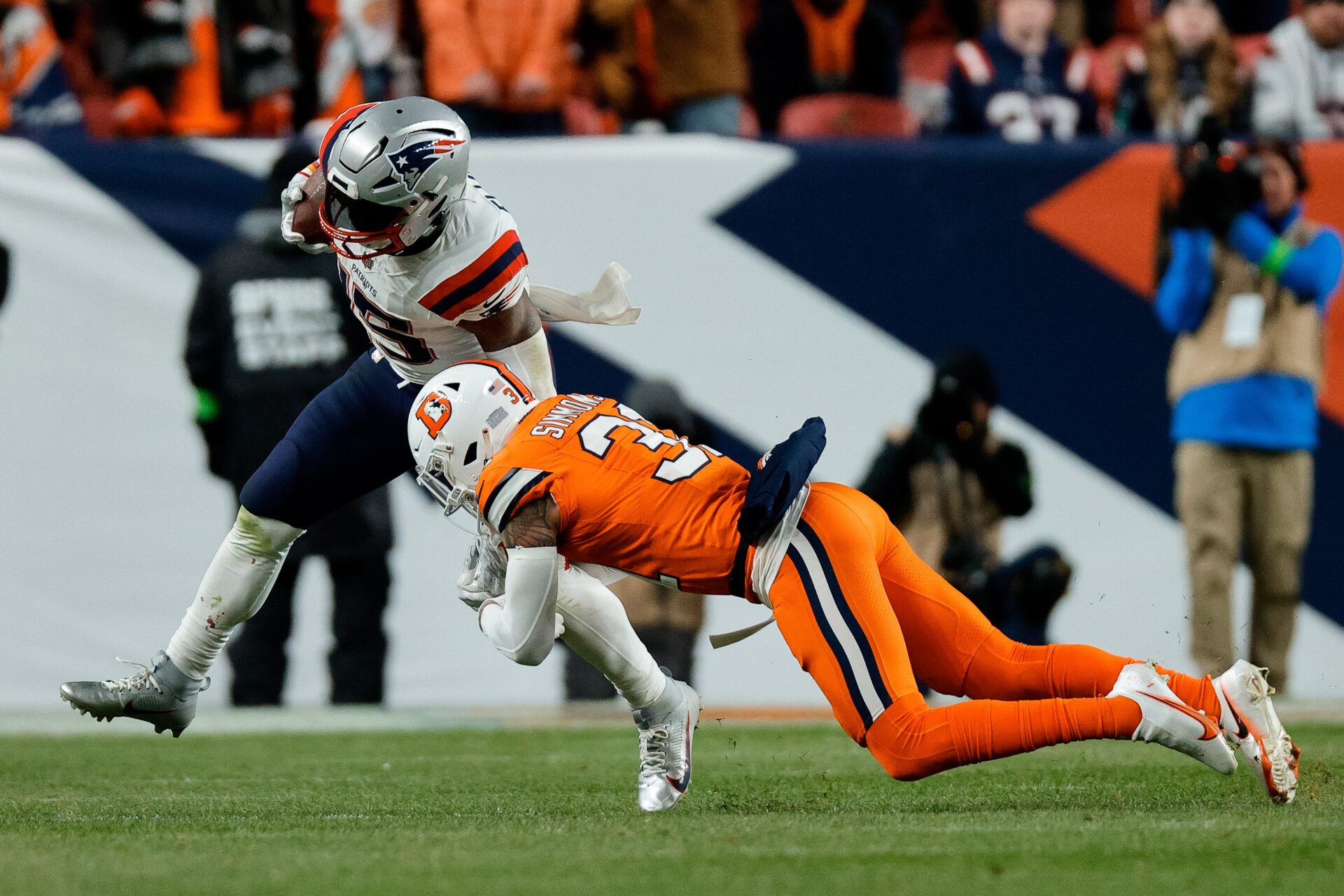 New England Patriots running back Ezekiel Elliott (15) is tackled by Denver Broncos safety Justin Simmons (31) in the fourth quarter at Empower Field at Mile High.