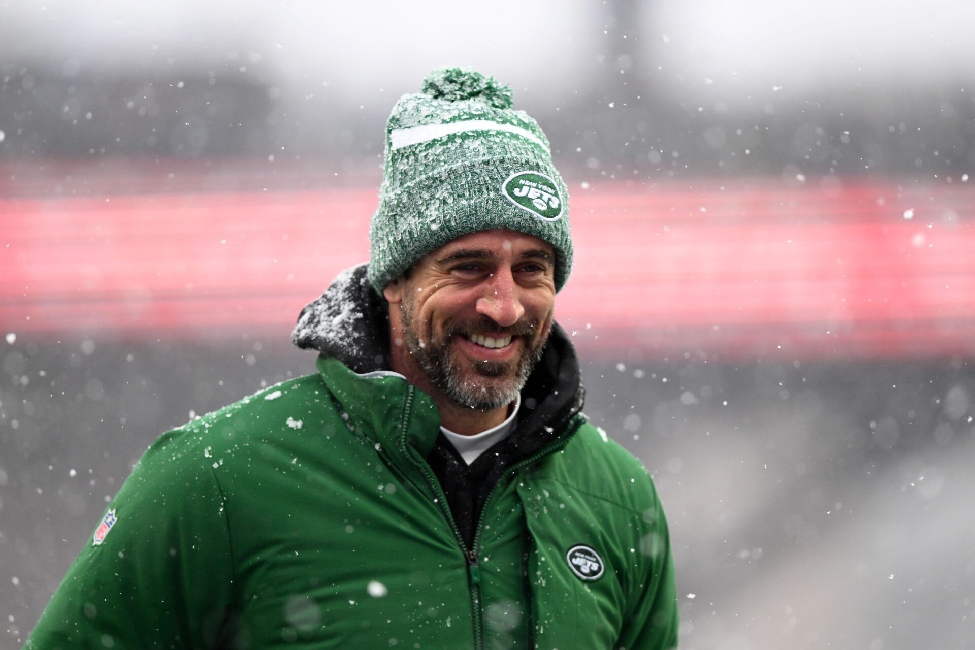 New York Jets QB Aaron Rodgers smiles as he walks off the field.