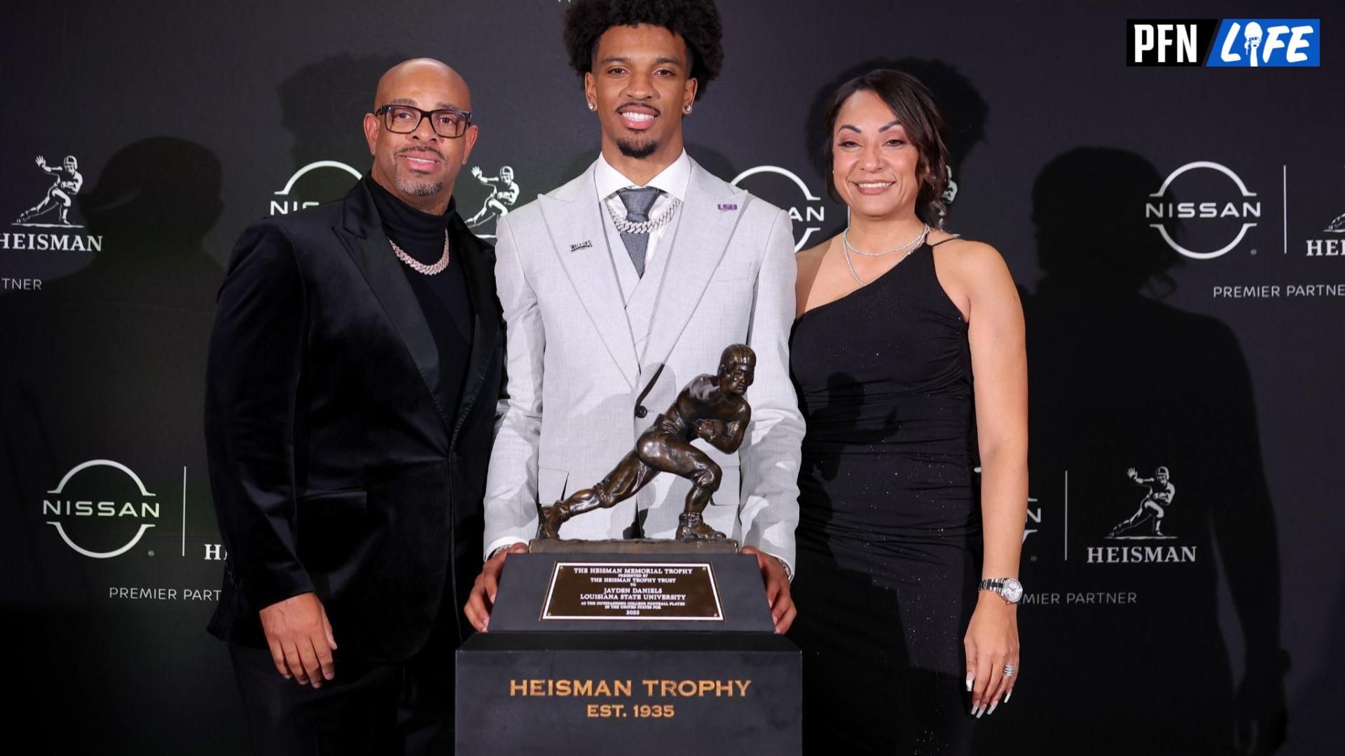 LSU Tigers QB Jayden Daniels poses with his parents after winning the Heisman Trophy.