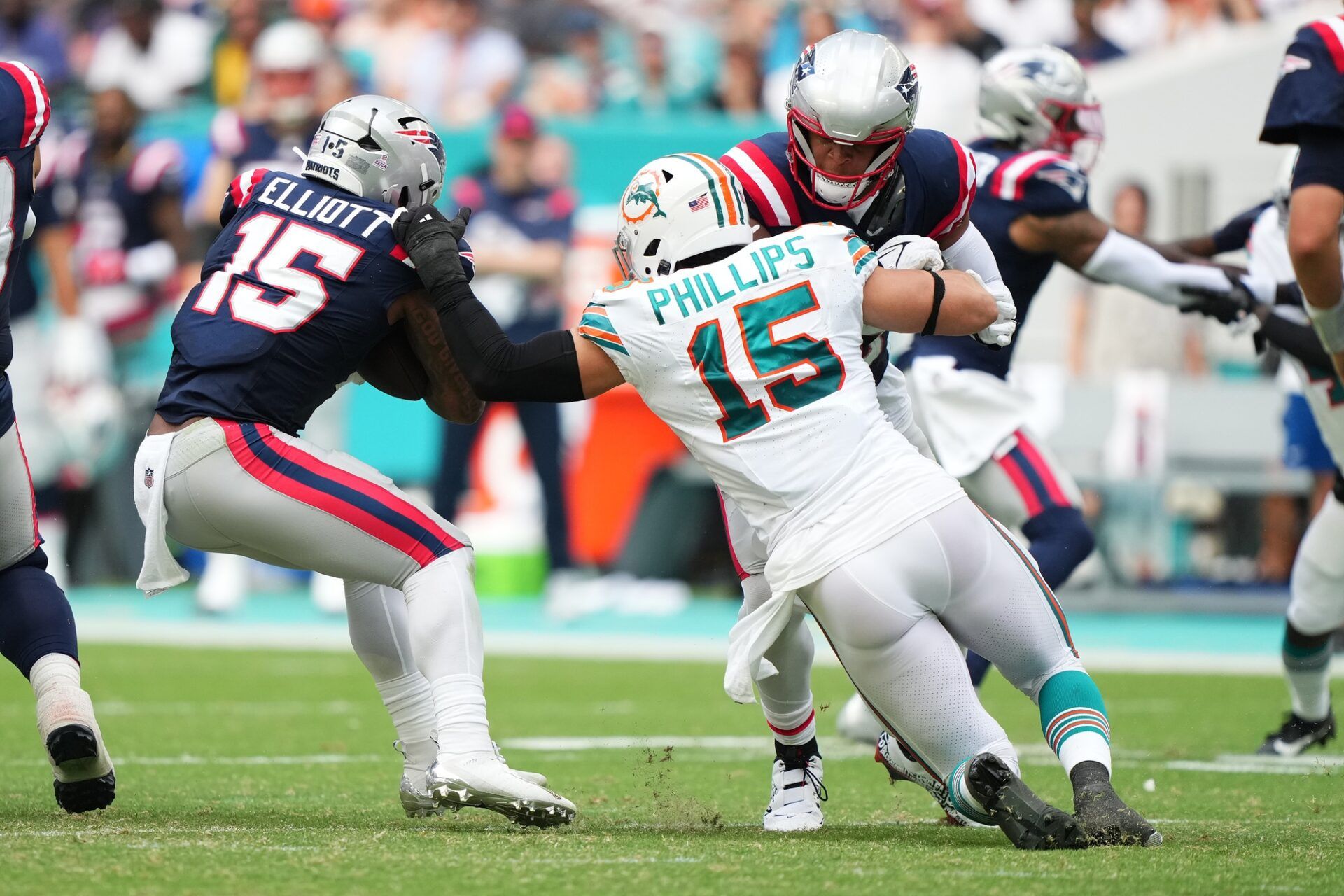 Miami Dolphins linebacker Jaelan Phillips (15) reaches for New England Patriots running back Ezekiel Elliott (15) during the second half at Hard Rock Stadium.