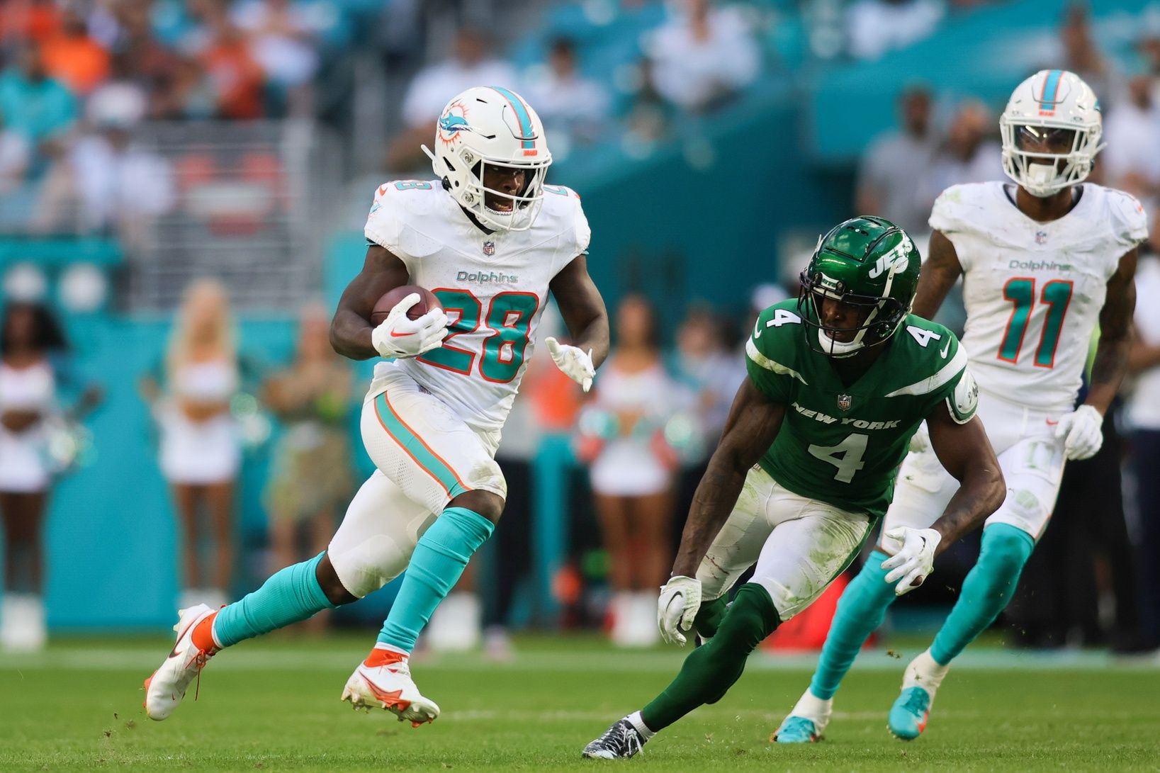 Miami Dolphins running back De'Von Achane (28) runs with the football against New York Jets cornerback D.J. Reed (4) during the fourth quarter at Hard Rock Stadium.