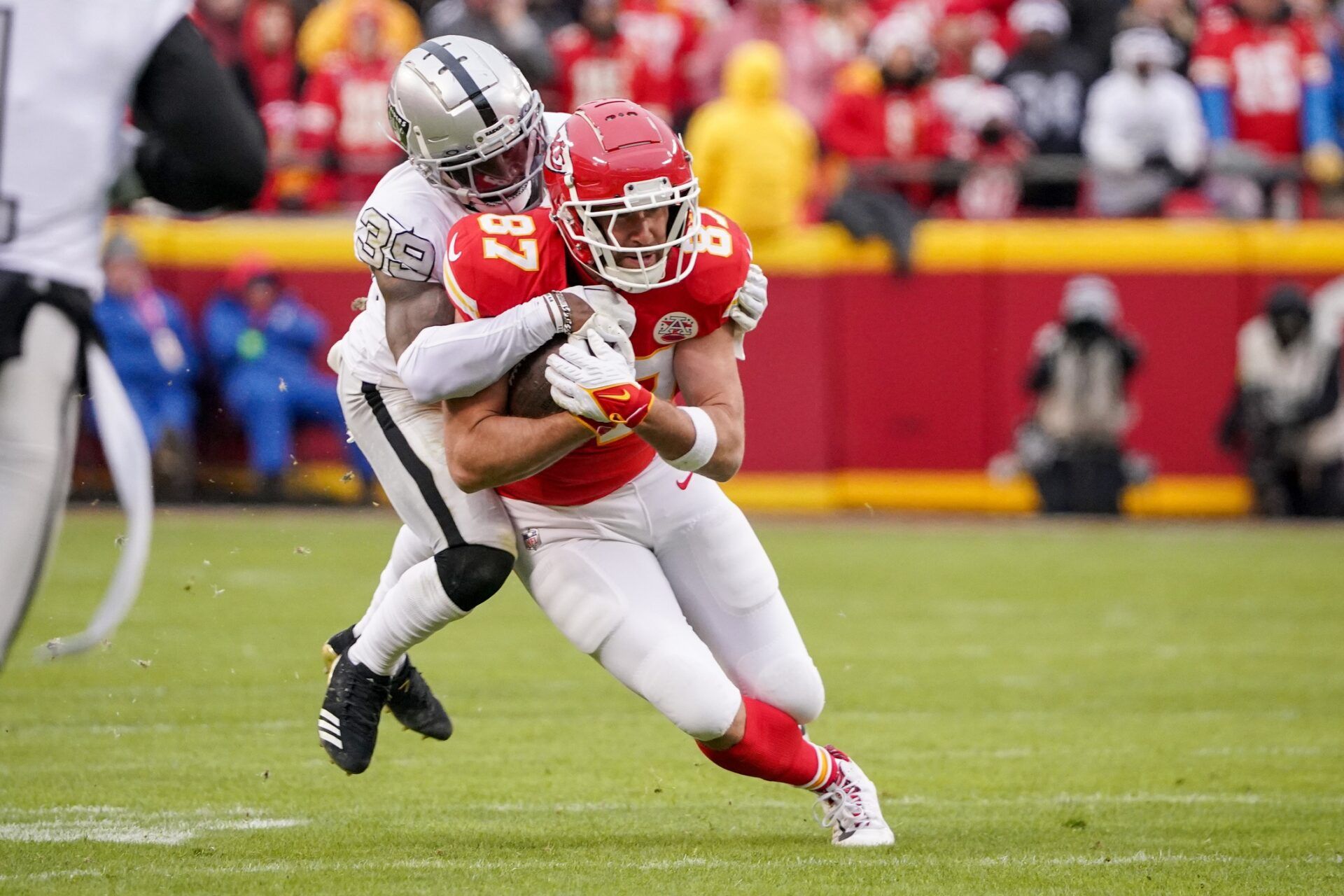 Kansas City Chiefs tight end Travis Kelce (87) runs the ball as Las Vegas Raiders cornerback Nate Hobbs (39) defends during the first half at GEHA Field at Arrowhead Stadium.