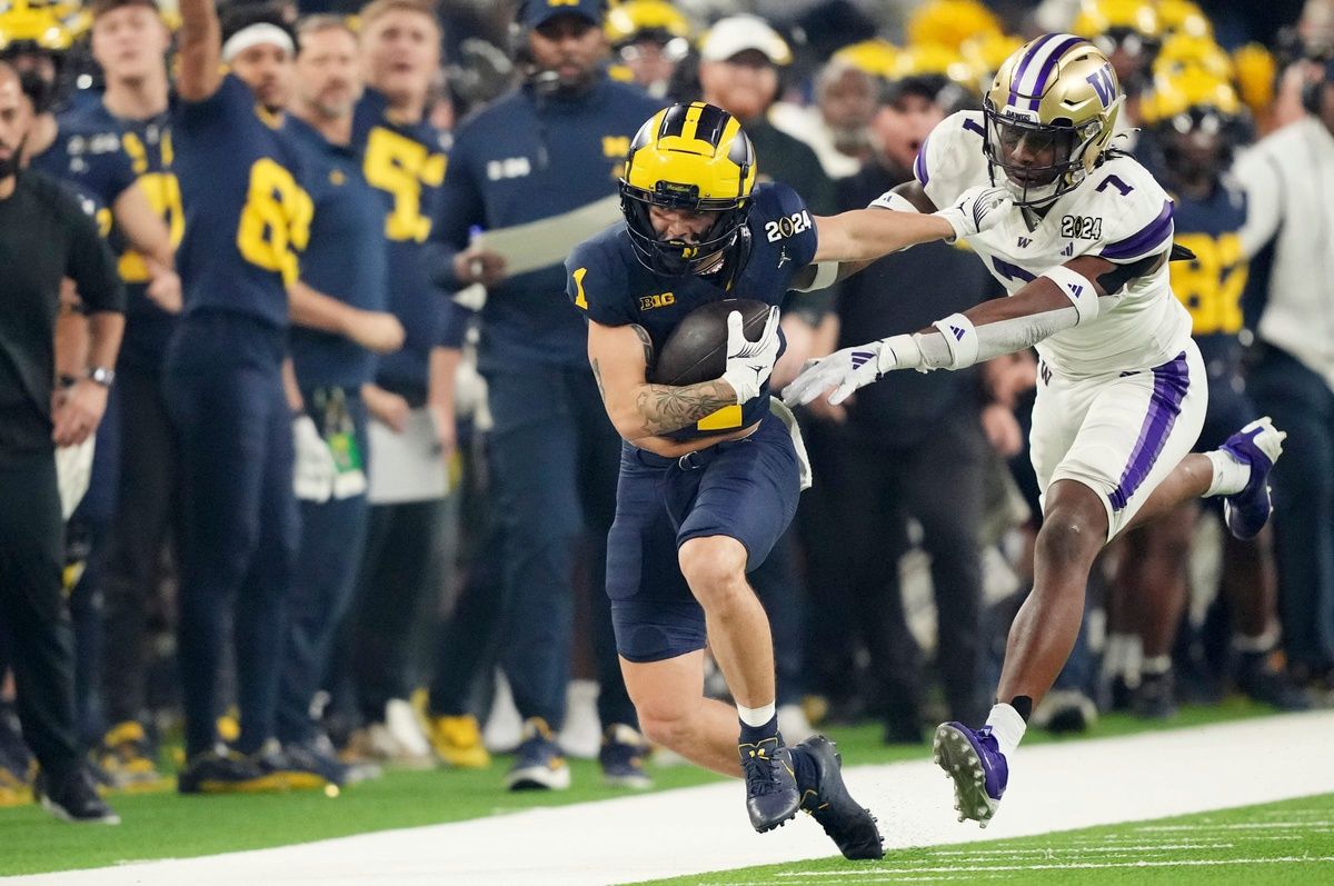 Michigan wide receiver Roman Wilson (1) runs the ball around Washington cornerback Dominique Hampton (7) during the first quarter of the College Football Playoff national championship game against Washington at NRG Stadium in Houston, Texas on Monday, January 8, 2024.