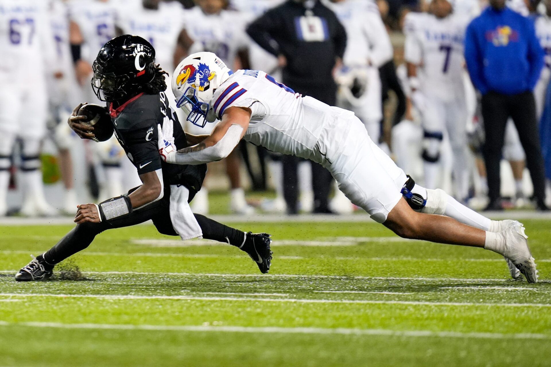 Cincinnati Bearcats quarterback Emory Jones (5) drives the ball as Kansas Jayhawks defensive lineman Austin Booker (9) tackles him to the ground during the NCAA college football game between the Cincinnati Bearcats and Kansas Jayhawks on Saturday, Nov. 25, 2023, at Nippert Stadium in Cincinnati. Kansas won 49-16.