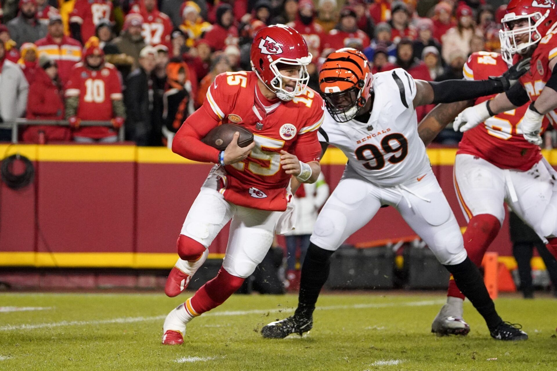 Kansas City Chiefs quarterback Patrick Mahomes (15) scrambles as Cincinnati Bengals defensive end Myles Murphy (99) pressures during the second half at GEHA Field at Arrowhead Stadium.