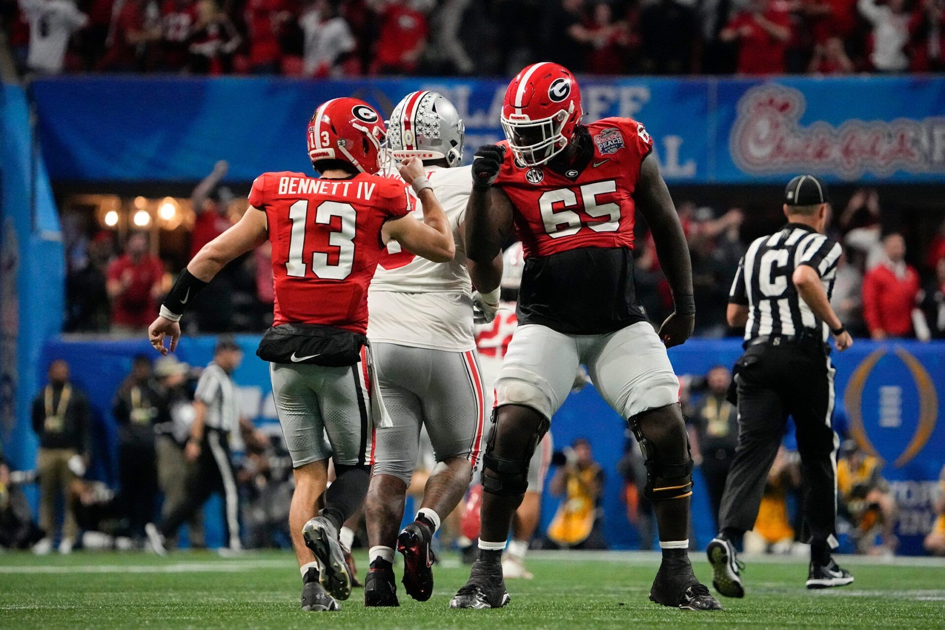 Georgia Bulldogs quarterback Stetson Bennett (13) gets a fist pump from offensive lineman Amarius Mims (65) after a touchdown pass during the second half of the Peach Bowl against the Ohio State Buckeyes in the College Football Playoff semifinal at Mercedes-Benz Stadium. Ohio State lost 42-41.