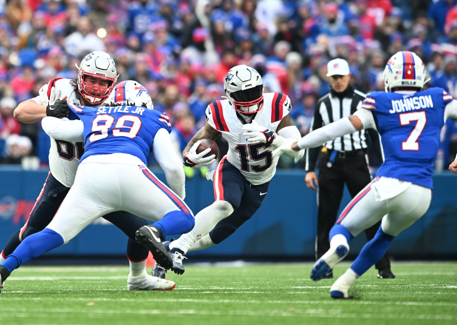 New England Patriots running back Ezekiel Elliott (15) runs against Buffalo Bills defensive tackle Tim Settle (99) and cornerback Taron Johnson (7) with a block by guard Atonio Mafi in the third quarter at Highmark Stadium.