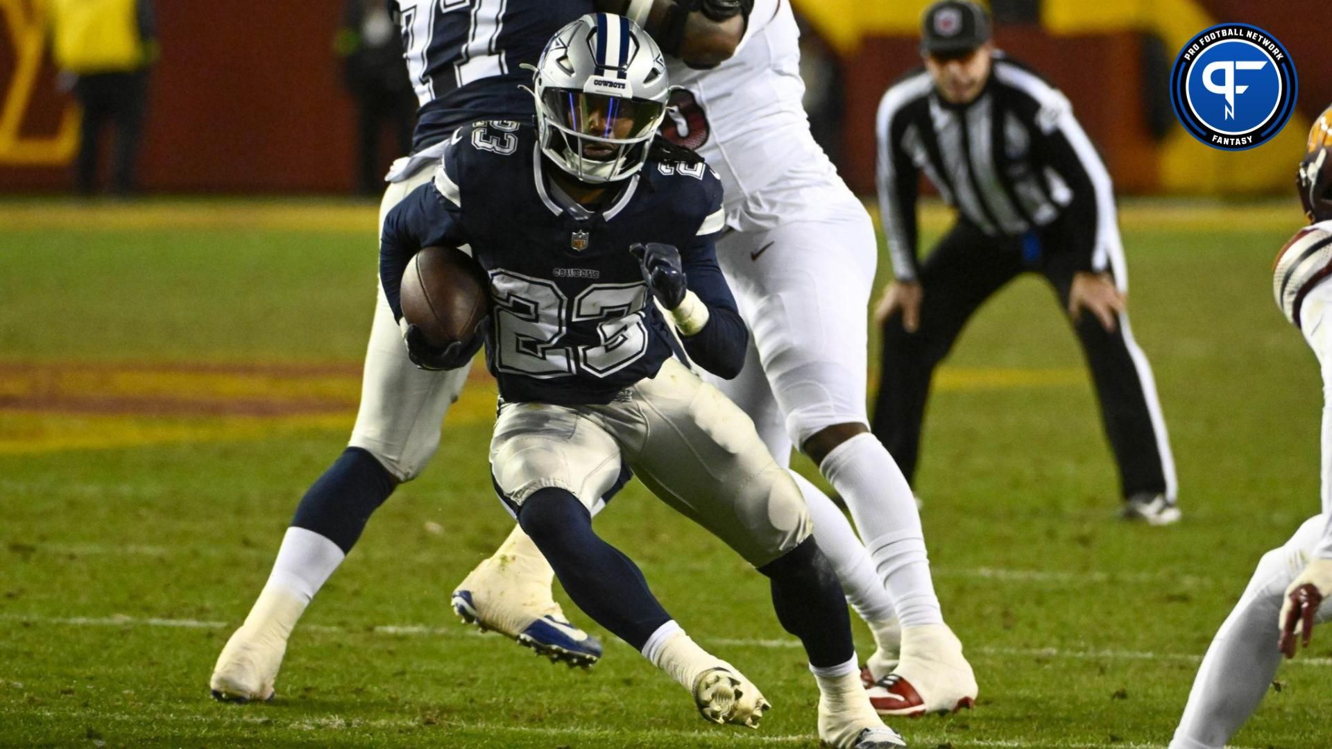 Dallas Cowboys running back Rico Dowdle (23) carries the ball past Washington Commanders safety Terrell Burgess (32) during the second half at FedExField.