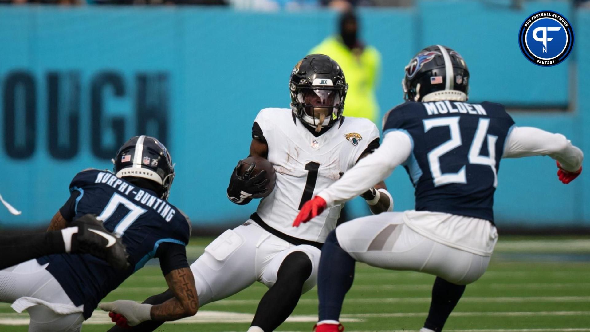 Jacksonville Jaguars running back Travis Etienne Jr. (1) is bottled-up for a loss by Tennessee Titans cornerback Elijah Molden (24) during their game at Nissan Stadium in Nashville, Tenn., Sunday, Jan. 7, 2024.