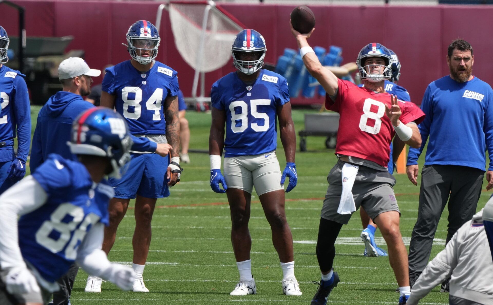 Several New York Giants players look on as QB Daniel Jones (8) throws a pass in practice.