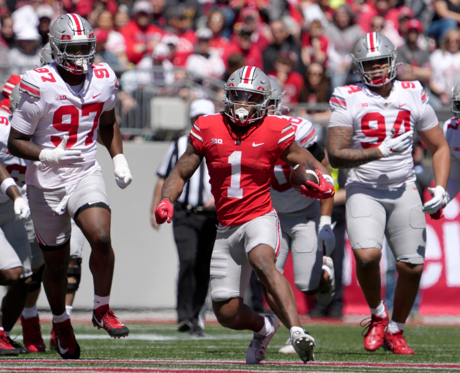 Ohio State Buckeyes running back Quinshon Judkins (1) runs the football for the scarlet team while pursued by defensive end Kenyatta Jackson Jr. (97) and Jason Moore (94) of the grey team during the first half of the LifeSports spring football game at Ohio Stadium on Saturday. Judkins lands in Minnesota in our lates Vikings mock draft.