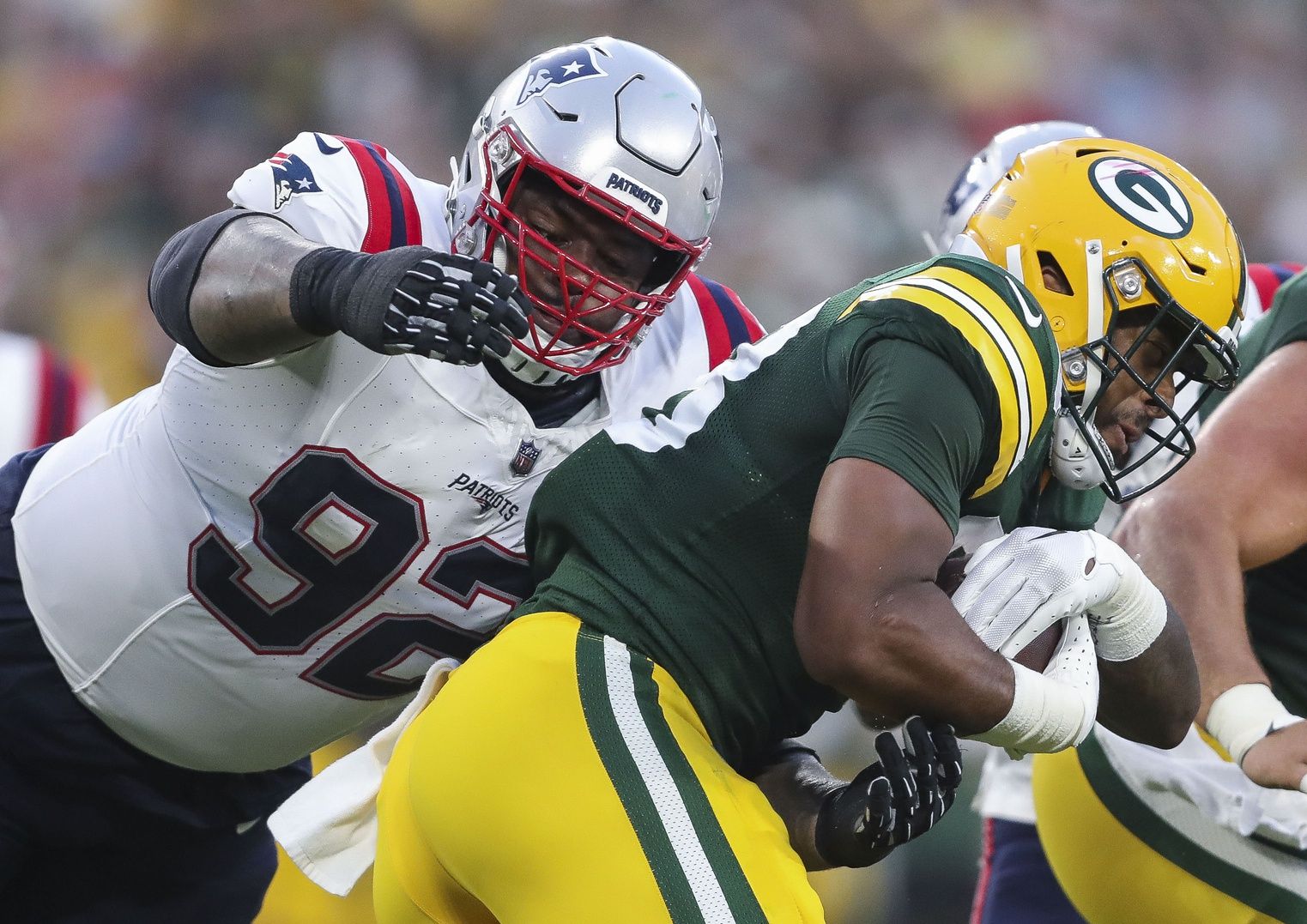 New England Patriots defensive tackle Davon Godchaux (92) tackles Green Bay Packers running back AJ Dillon (28) during their preseason football game at Lambeau Field. Mandatory Credit: Tork Mason-USA TODAY Sports