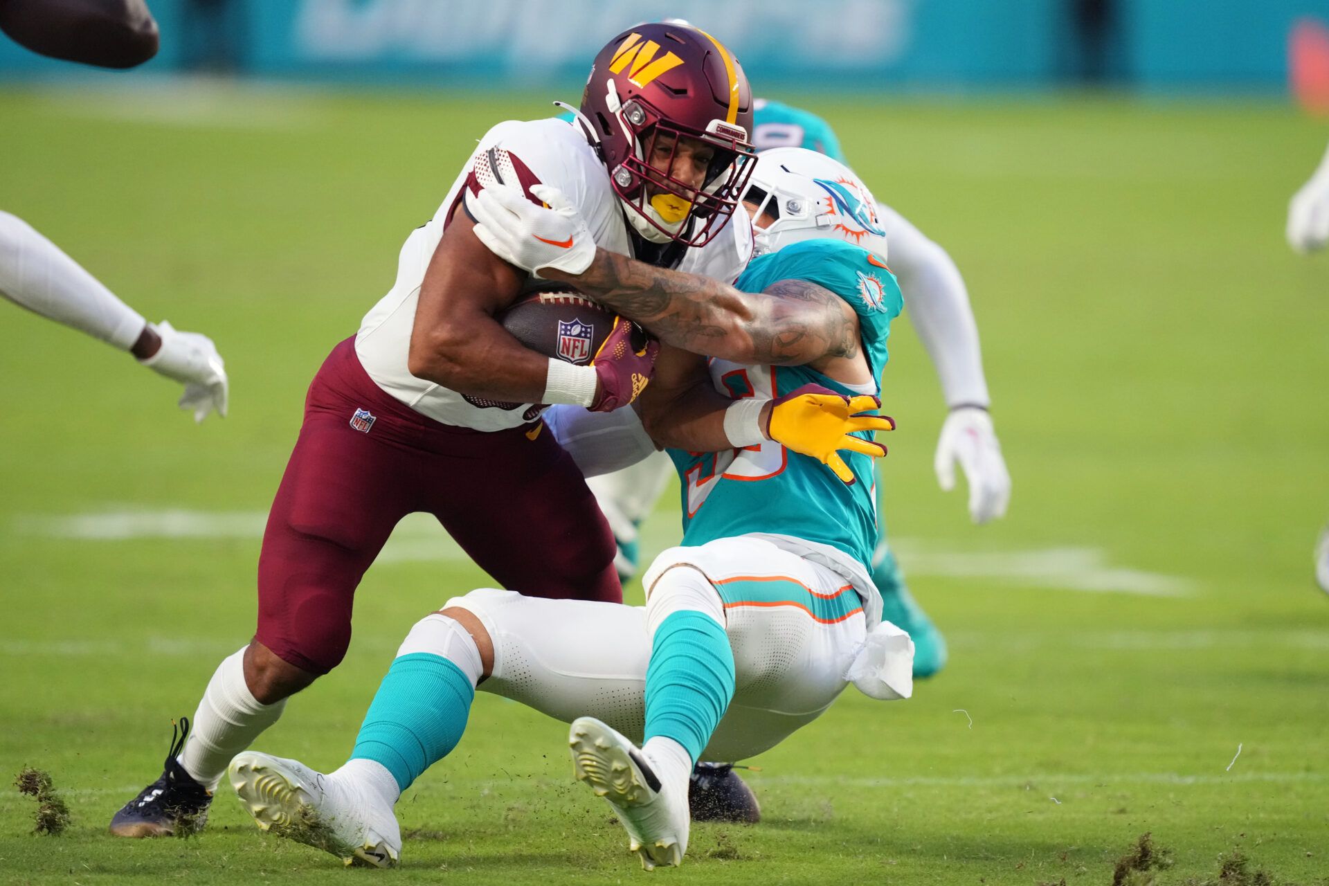 Aug 17, 2024; Miami Gardens, Florida, USA; Washington Commanders running back Austin Ekeler (30) gains a few yards Miami Dolphins linebacker Curtis Bolton (58) closes in for the tackle during the first quarter at Hard Rock Stadium. Mandatory Credit: Jim Rassol-USA TODAY Sports