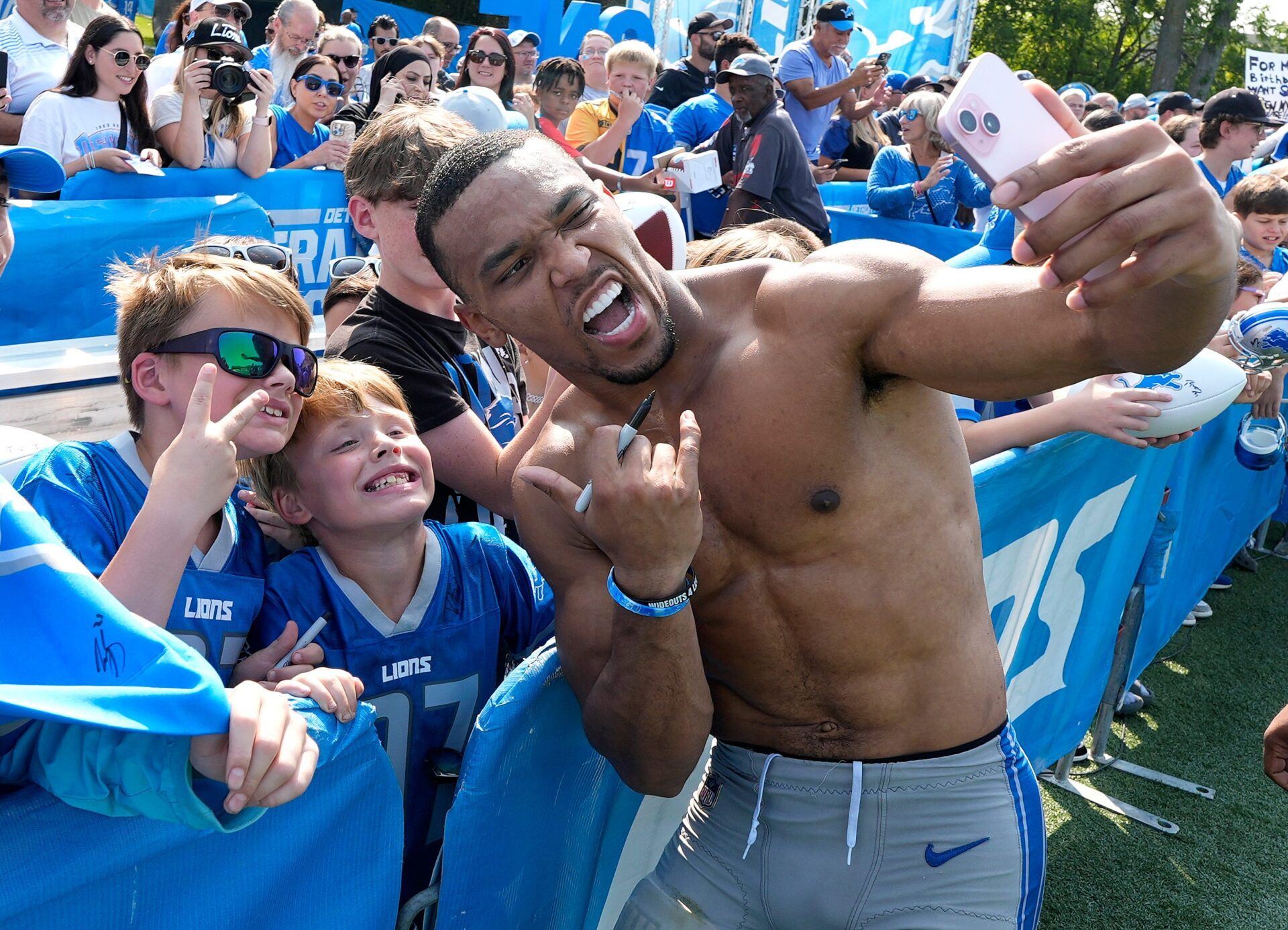 Detroit Lions wide receiver Amon-Ra St. Brown uses someoneÕs iPhone to do a selfie with kids after practice at the Detroit Lions training facility in Allen Park on Wednesday, August 14, 2024.