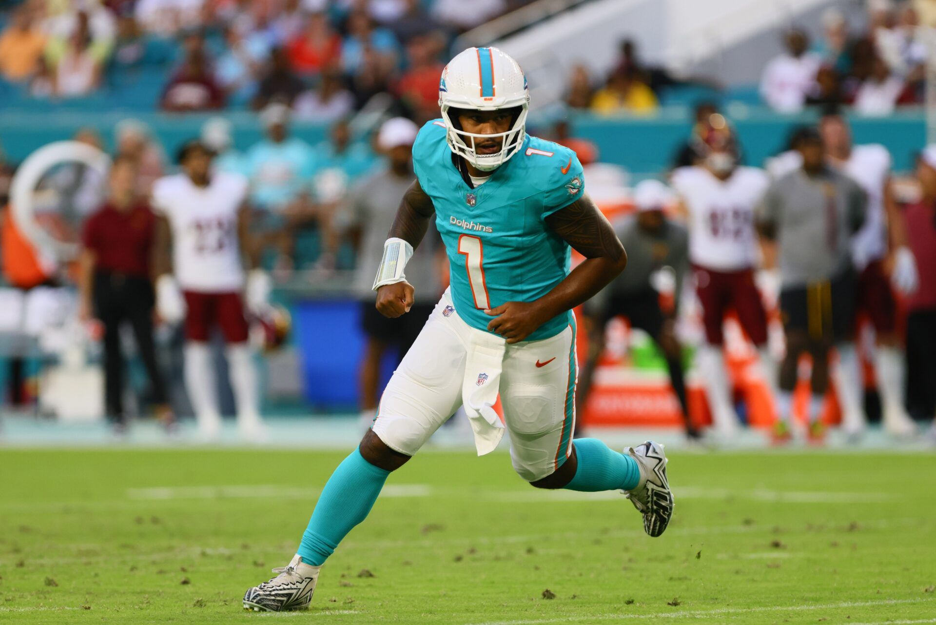 Miami Dolphins quarterback Tua Tagovailoa (1) runs on the field after passing the football against the Washington Commanders during the first quarter of a preseason game at Hard Rock Stadium. Mandatory Credit: Sam Navarro-USA TODAY Sports