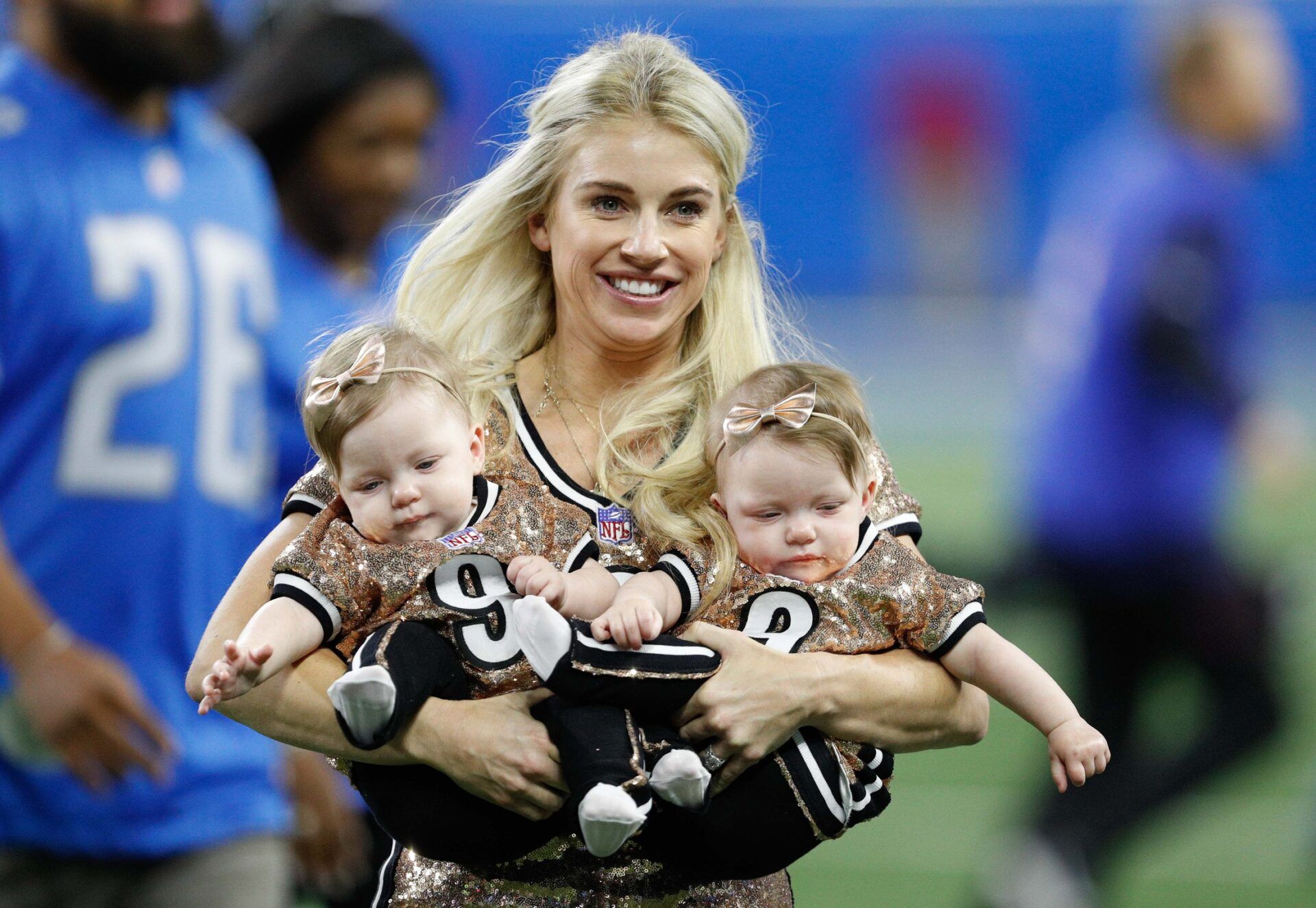 Detroit Lions quarterback Matthew Staffords wife Kelly Hall Stafford carries their twin girls off the field before the game against the Minnesota Vikings at Ford Field.