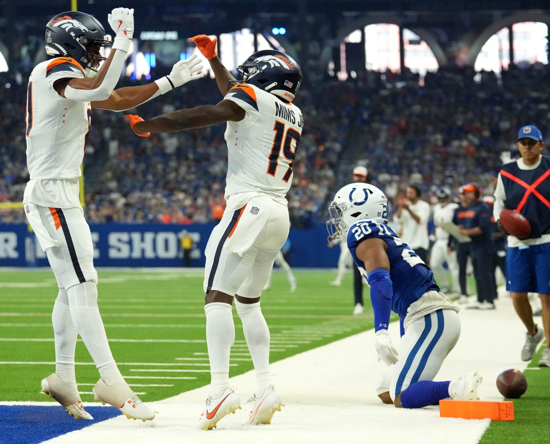 Denver Broncos wide receiver Devaughn Vele (81) and wide receiver Marvin Mims Jr. (19) celebrate a touchdown as Indianapolis Colts safety Nick Cross (20) looks on during the first half of a preseason game Sunday, Aug. 11, 2024, at Lucas Oil Stadium in Indianapolis.