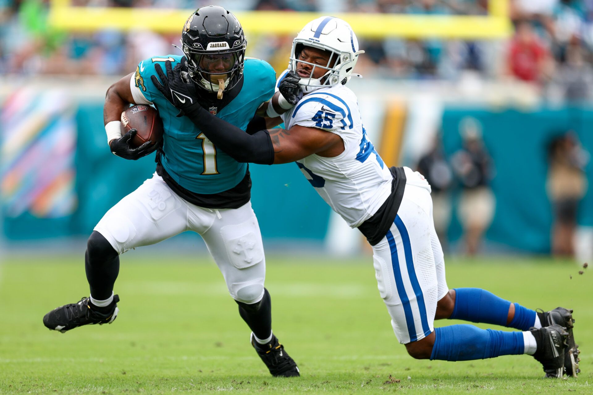 Oct 6, 2024; Jacksonville, Florida, USA; Jacksonville Jaguars running back Travis Etienne Jr. (1) holds off Indianapolis Colts linebacker E.J. Speed (45) in the first quarter at EverBank Stadium. Mandatory Credit: Nathan Ray Seebeck-Imagn Images