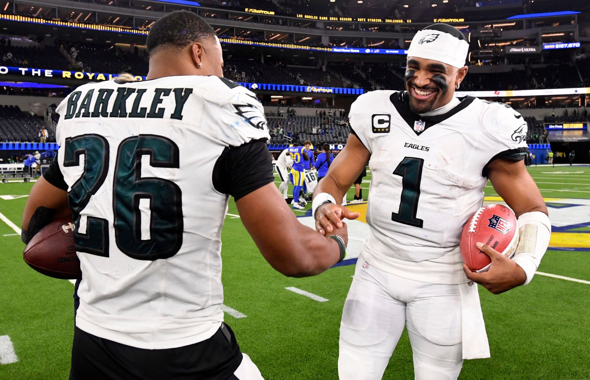 Nov 24, 2024; Inglewood, California, USA; Philadelphia Eagles quarterback Jalen Hurts (1) celebrates with running back Saquon Barkley (26) after the Eagles defeat the Los Angeles Rams during the first half at SoFi Stadium. Mandatory Credit: Alex Gallardo-Imagn Images