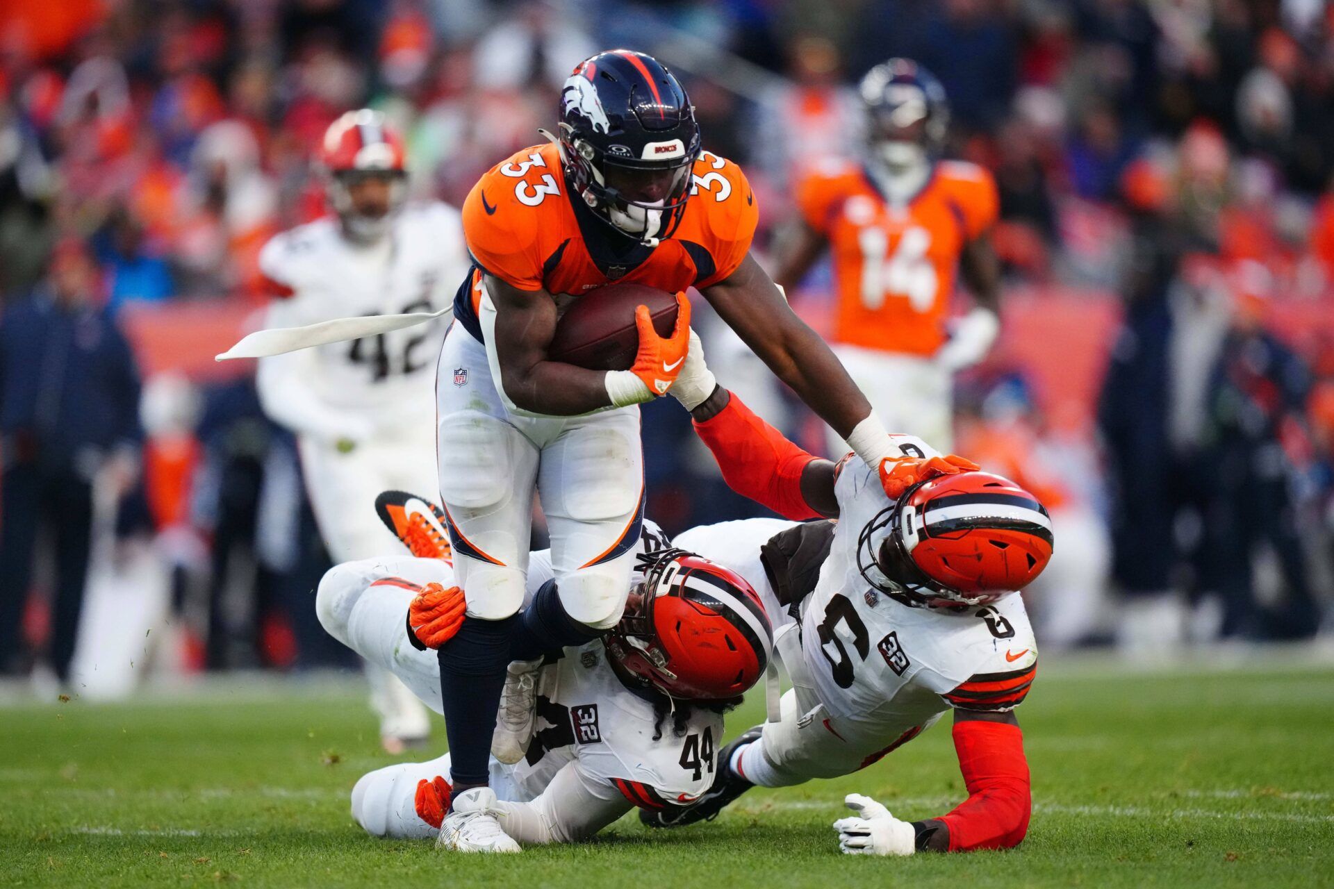 Denver Broncos running back Javonte Williams (33) carries the ball over Cleveland Browns linebacker Jeremiah Owusu-Koramoah (6) and linebacker Sione Takitaki (44) in the second half at Empower Field at Mile High.