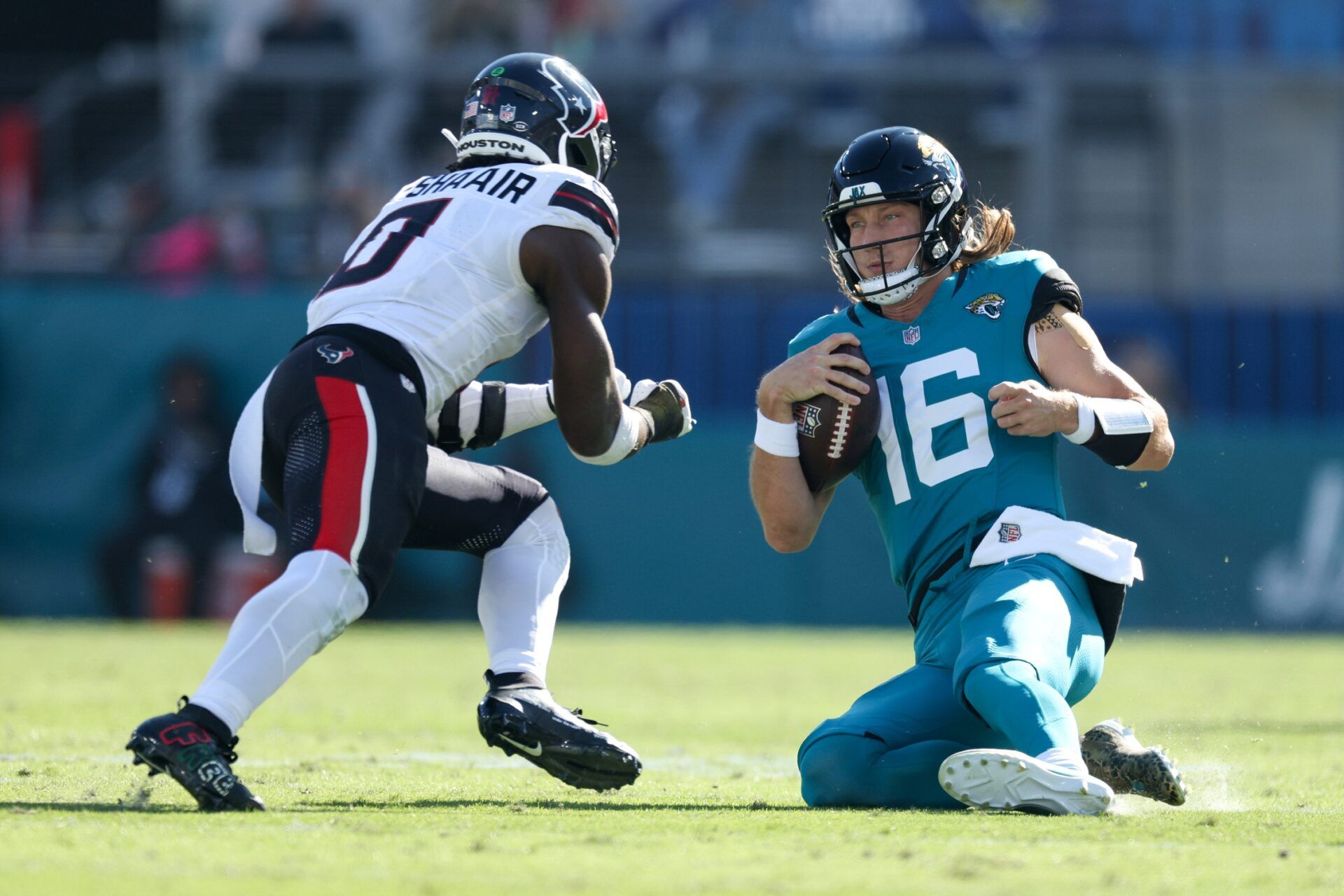 Jacksonville Jaguars quarterback Trevor Lawrence (16) slides down in front of Houston Texans linebacker Azeez Al-Shaair (0) in the second quarter in the second quarter at EverBank Stadium.