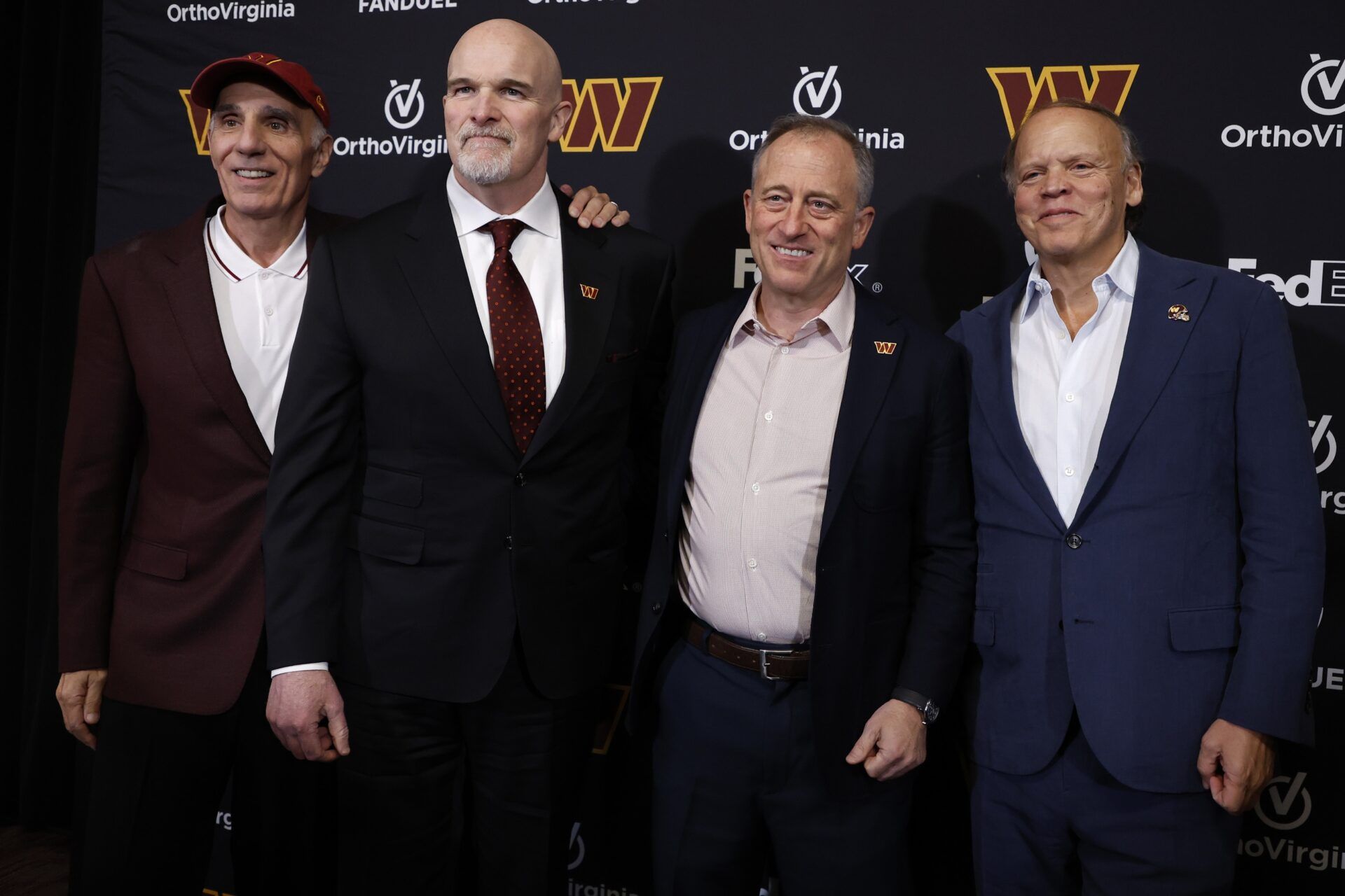 Washington Commanders limited partner Mitch Rales, Commanders head coach Dan Quinn, Commanders majority owner Josh Harris, and Commanders limited partner Mark Ein pose for a picture at Quinn's introductory press conference at Commanders Park.