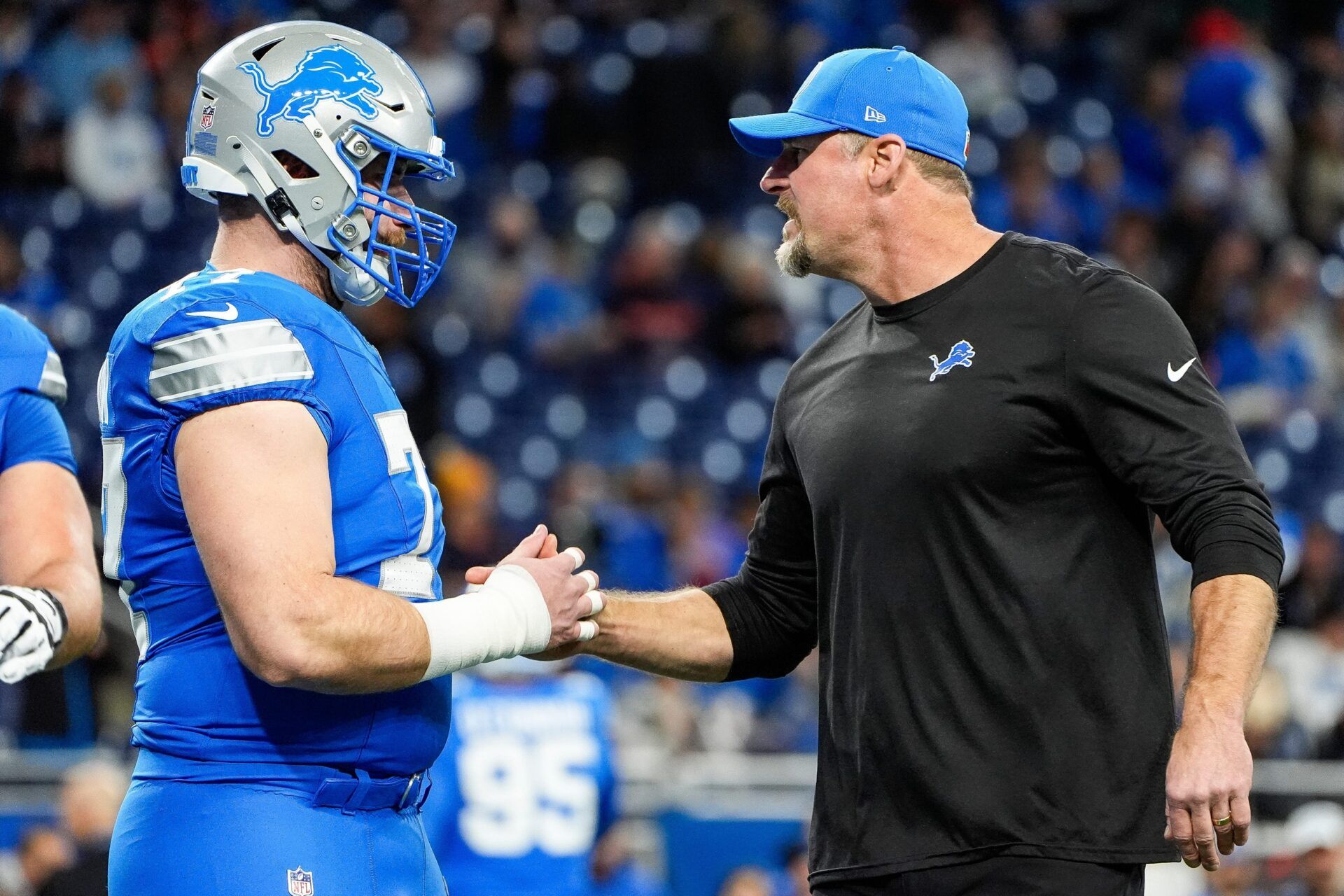 Detroit Lions head coach Dan Campbell shakes hands with center Frank Ragnow (77) warm up before the game between Detroit Lions and Chicago Bears at Ford Field in Detroit on Thursday, Nov. 28, 2024.