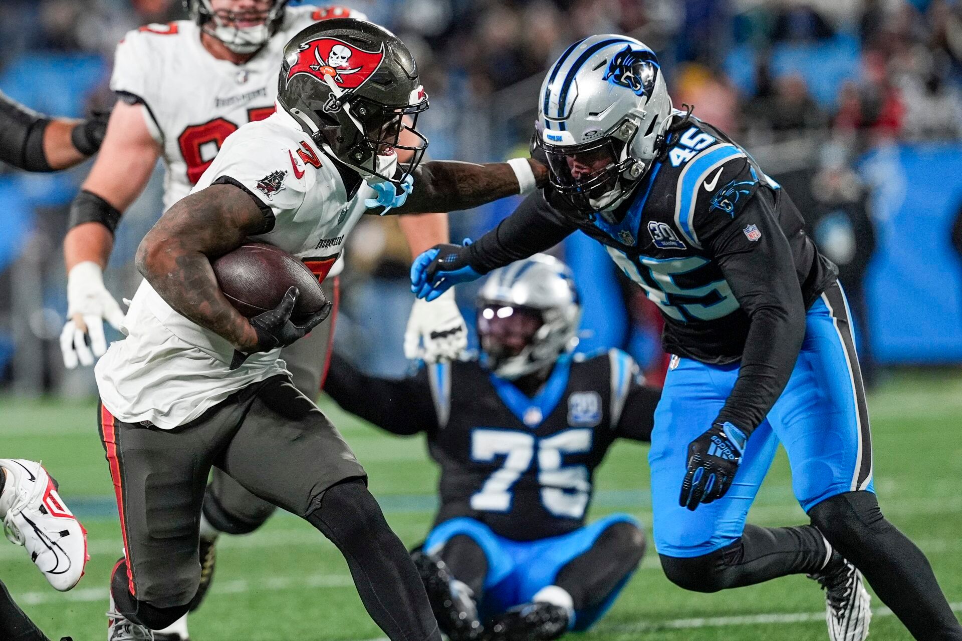 Dec 1, 2024; Charlotte, North Carolina, USA; Tampa Bay Buccaneers running back Bucky Irving (7) tries to hold back Carolina Panthers linebacker Cam Gill (45) during the second half at Bank of America Stadium. Mandatory Credit: Jim Dedmon-Imagn Images