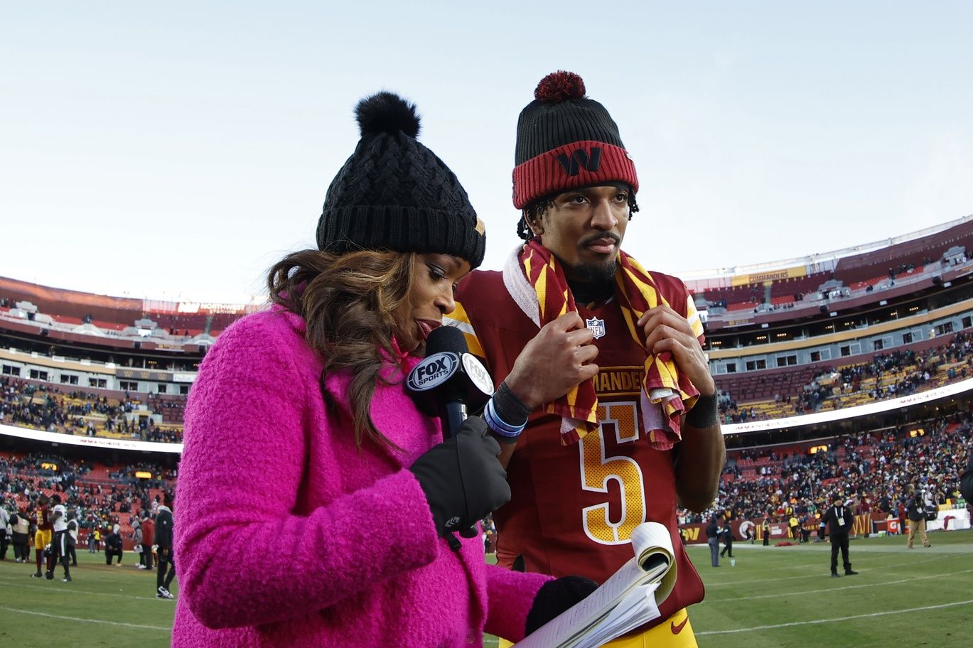 Washington Commanders quarterback Jayden Daniels (5) prepares to give an interview with Fox Sports reporter Pam Oliver (L) after the Commanders' game against the Philadelphia Eagles at Northwest Stadium.