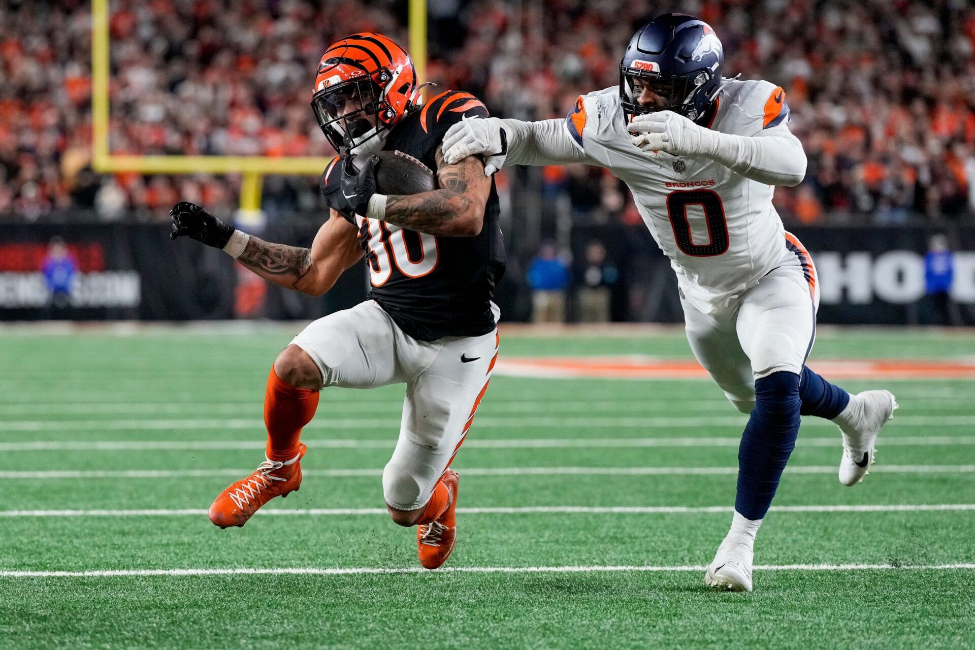 Cincinnati Bengals running back Chase Brown (30) is stopped short of the end zone by Denver Broncos linebacker Jonathon Cooper (0) on a carry in the fourth quarter of the NFL Week 17 game between the Cincinnati Bengals and the Denver Broncos at Paycor Stadium in downtown Cincinnati on Saturday, Dec. 28, 2024. The Bengals took a 30-24 win in overtime to remain in the post season chase.