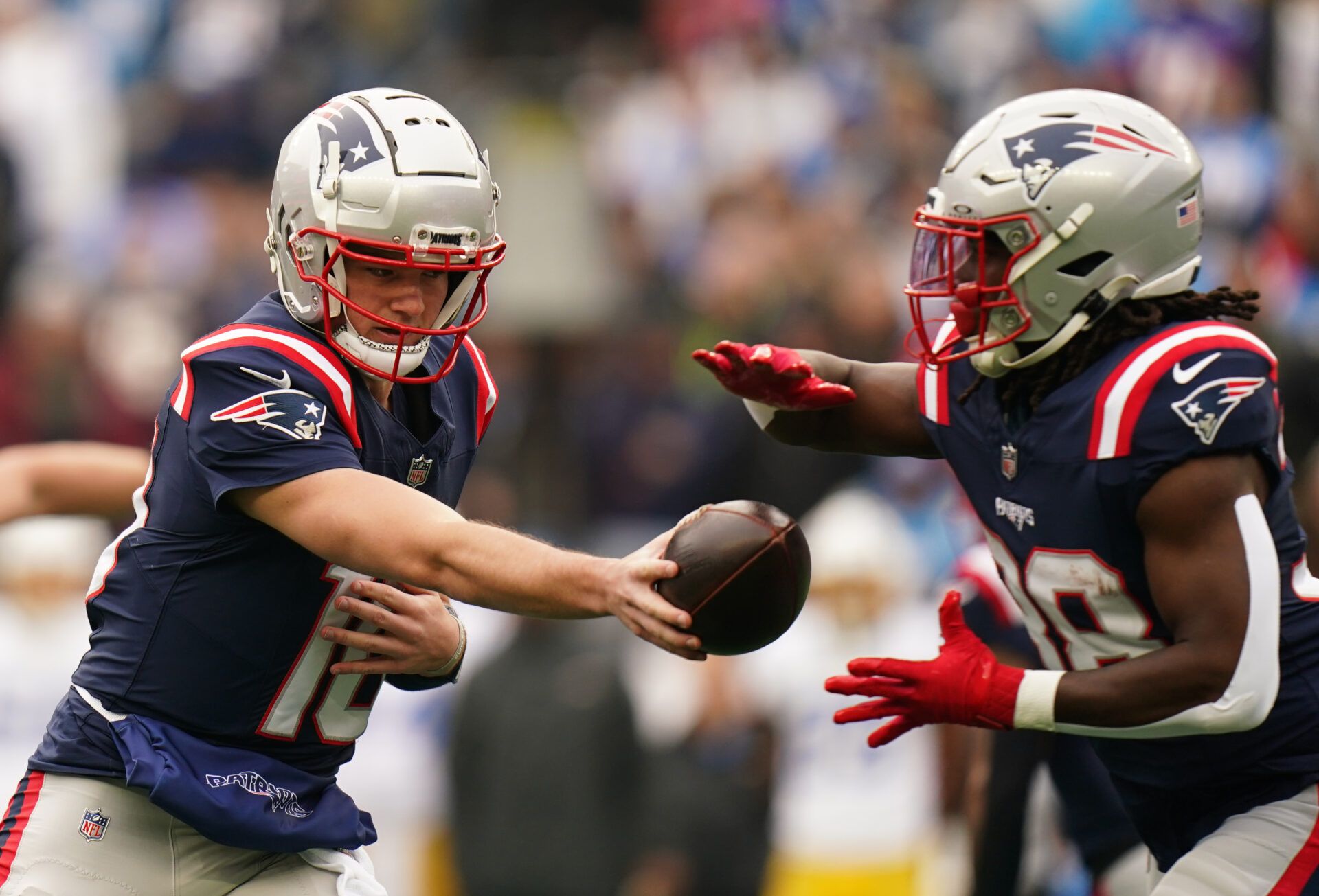 Dec 28, 2024; Foxborough, Massachusetts, USA; New England Patriots quarterback Drake Maye (10) hands off the ball to running back Rhamondre Stevenson (38) against the Los Angeles Chargers in the first quarter at Gillette Stadium. Mandatory Credit: David Butler II-Imagn Images