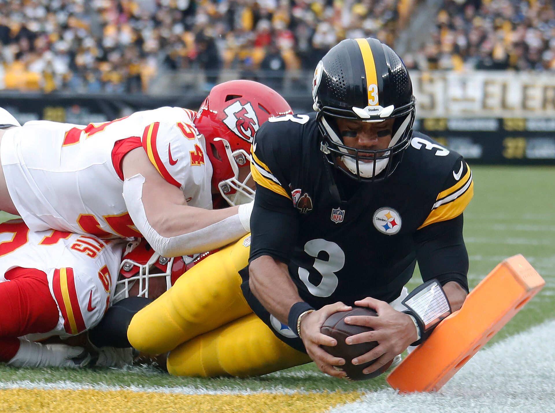 Dec 25, 2024; Pittsburgh, Pennsylvania, USA; Pittsburgh Steelers quarterback Russell Wilson (3) dives for the end-zone to score a touchdown past Kansas City Chiefs defensive end George Karlaftis (56) and linebacker Leo Chenal (54) during the second quarter at Acrisure Stadium. Mandatory Credit: Charles LeClaire-Imagn Images