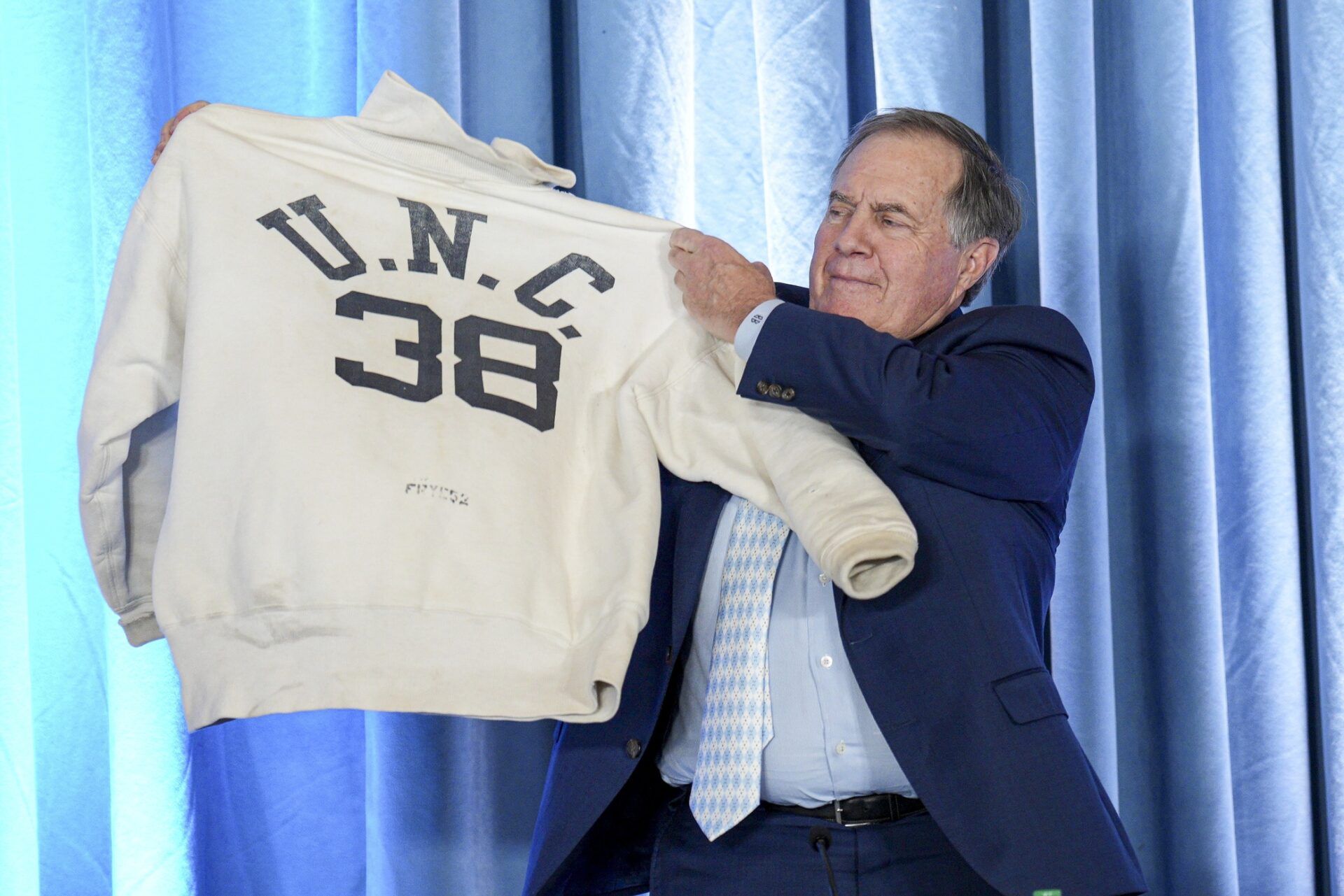 North Carolina Tar Heels new head coach Bill Belichick holds up the sweatshirt worn by his father when he was an assistant coach at New North Carolina Tar Heels new at Loudermilk Center for Excellence.