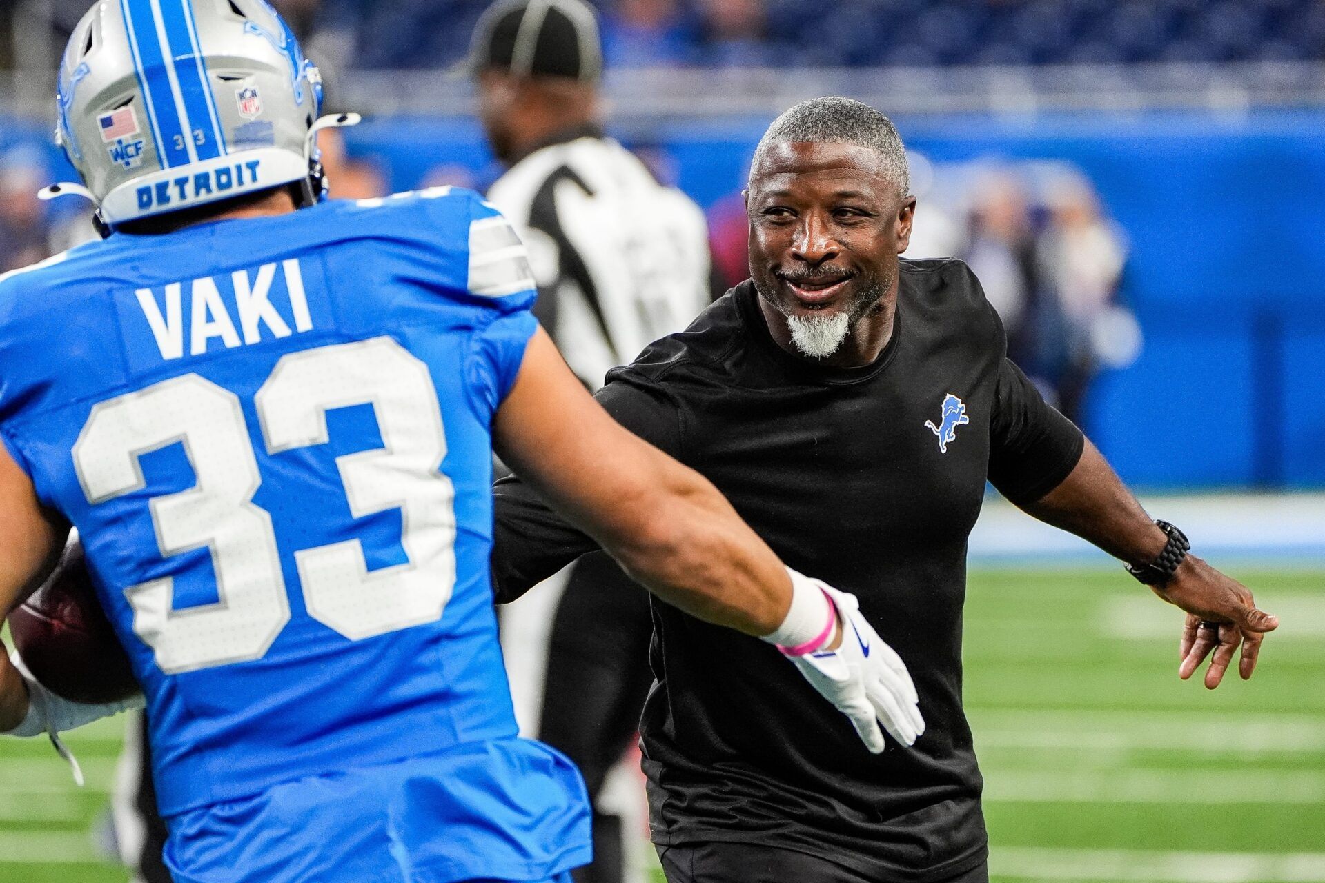 Detroit Lions defensive coordinator Aaron Glenn shakes hands with running back Sione Vaki (33) during warm up before the Tennessee Titans game at Ford Field in Detroit on Sunday, Oct. 27, 2024.